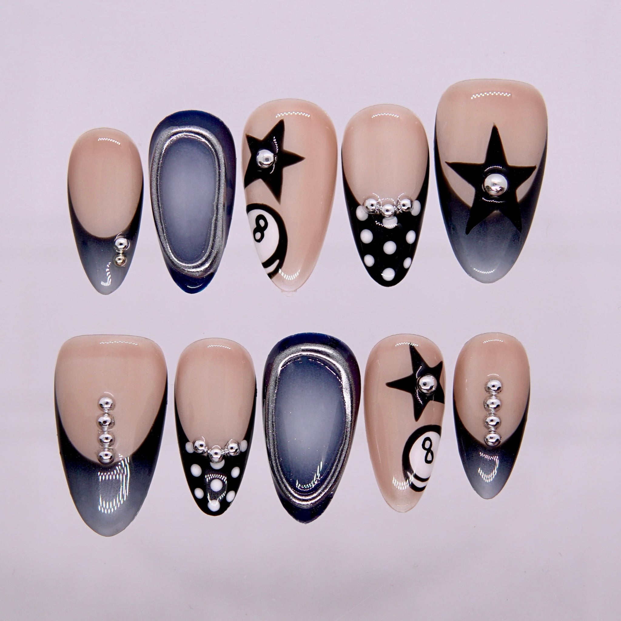 Eight Ball Baby press-on nails in smoky nude tones with 8-ball pattern, chrome edges, and star details.