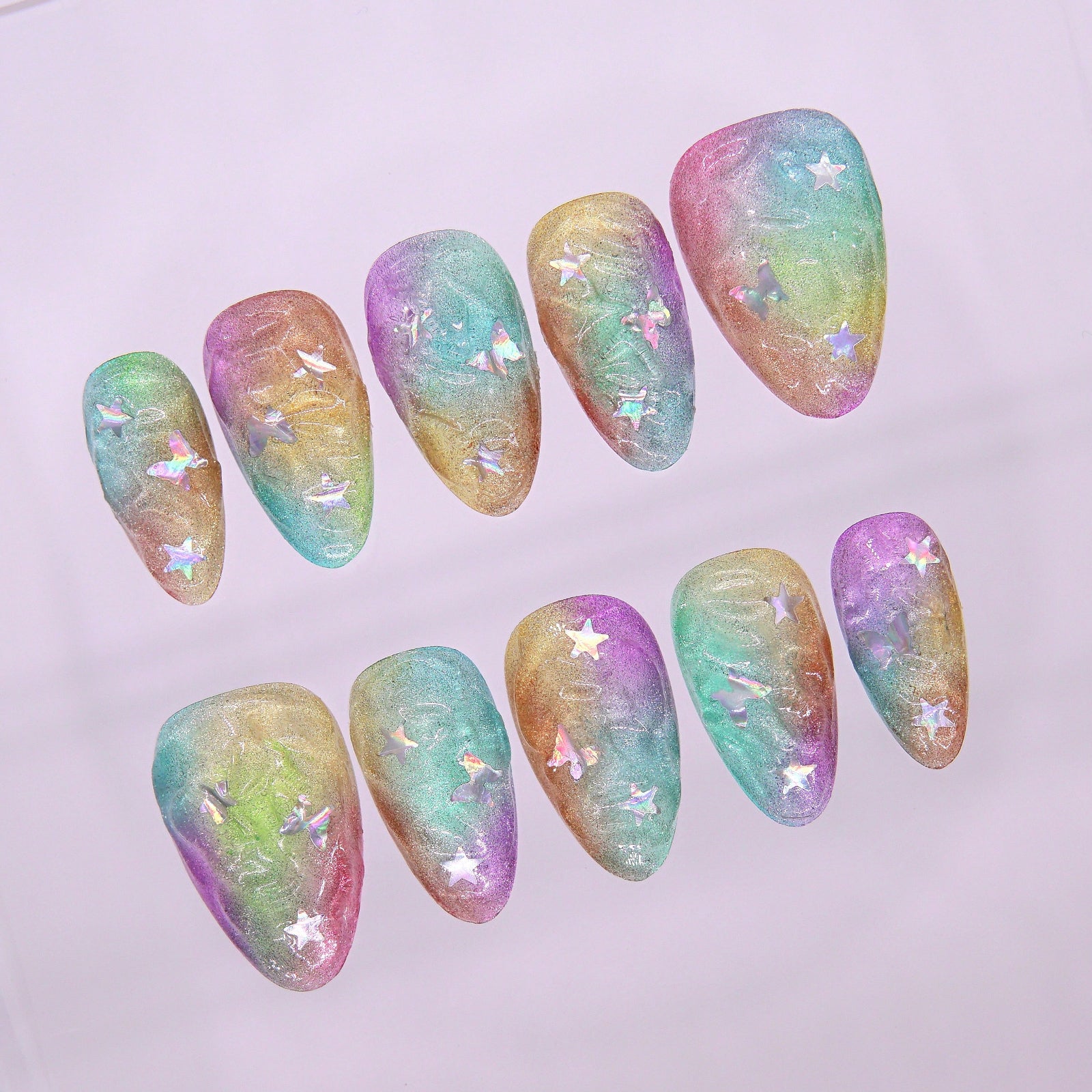 Close-up of nail with pastel cloud-like texture and translucent star confetti.