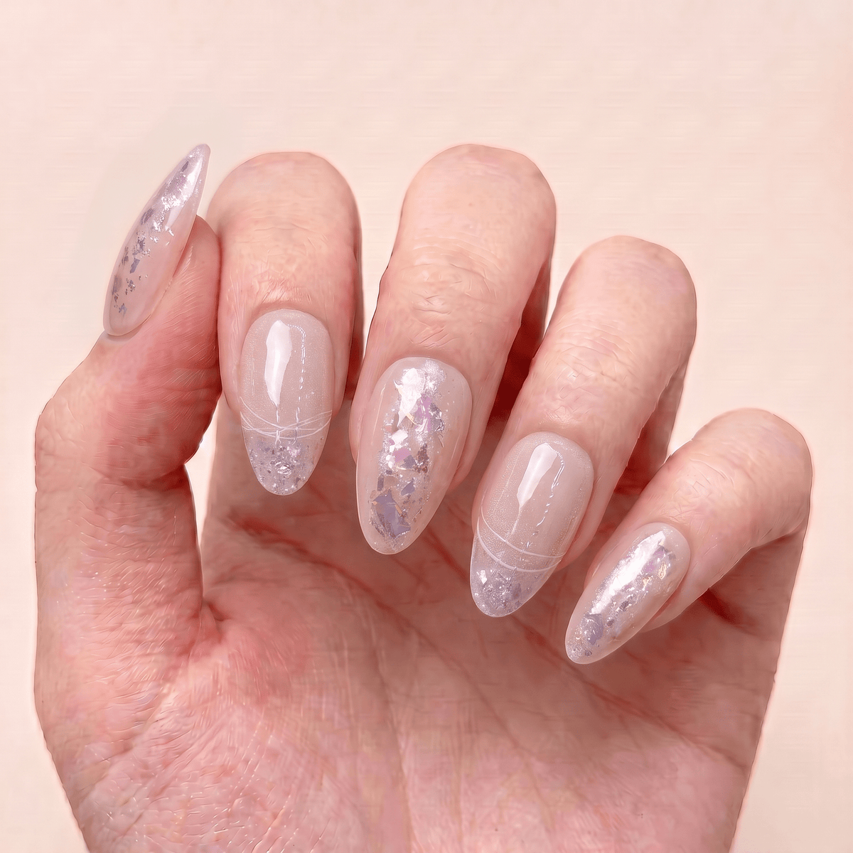 Fairydust Whisper handmade press-on nails worn on hand with sheer nude pink tones, iridescent flakes, and soft shimmering details