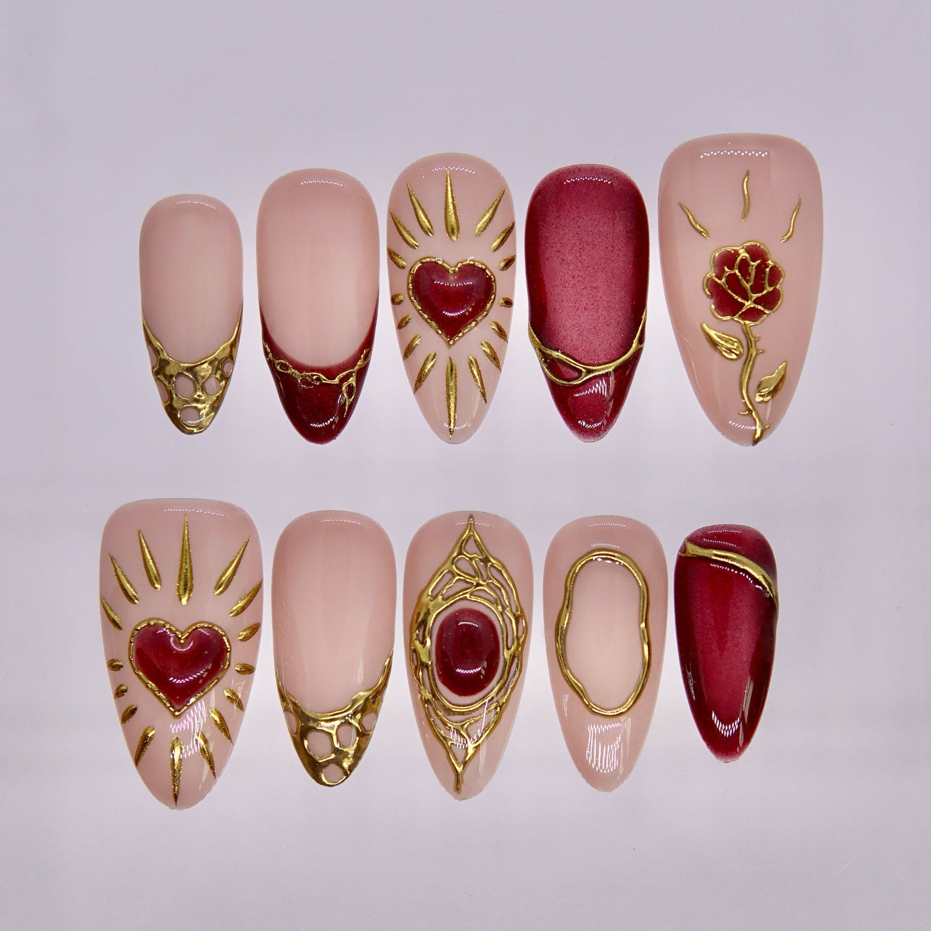 Dragon zodiac press-on nails with nude base, deep crimson accents, and ornate gold detailing including heart and rose motifs, representing Fate self love energy.
