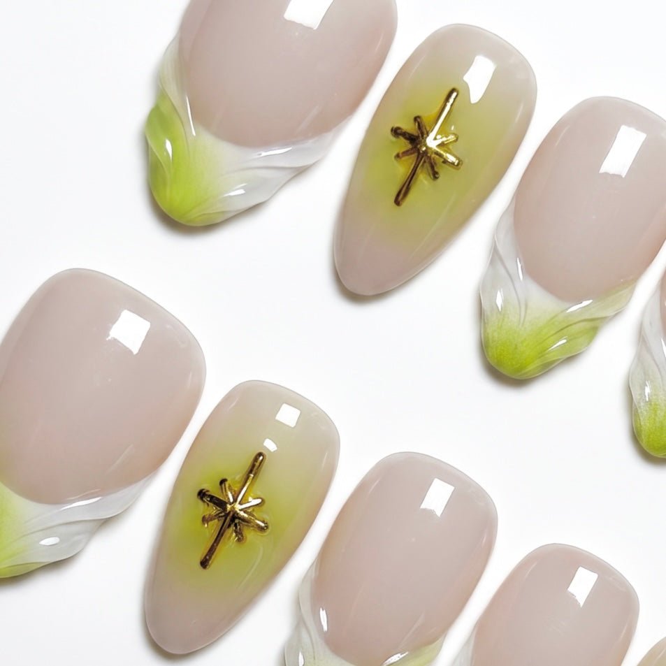 Close-up of handmade nude and lime French tip nails with gold star embellishments and glossy finish.