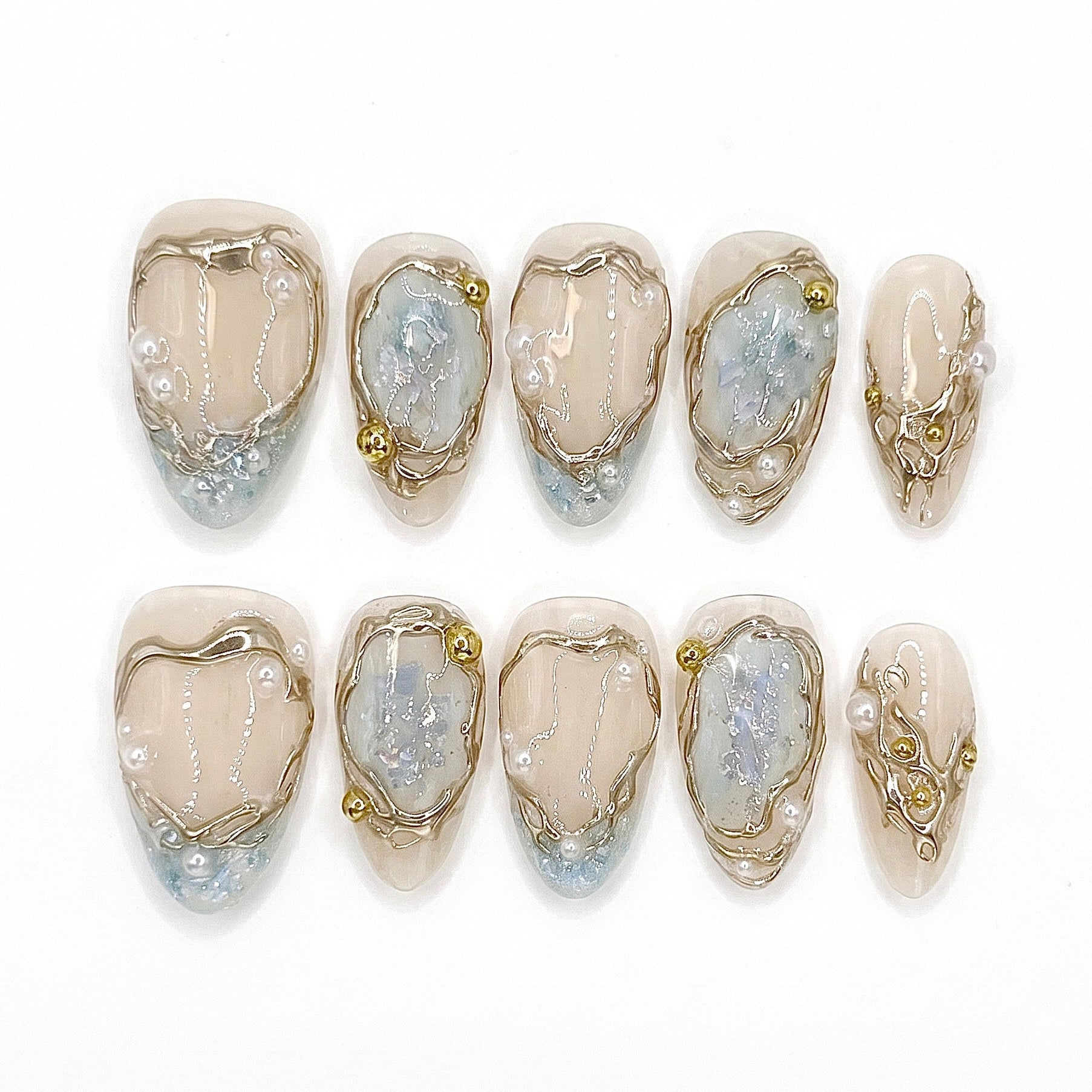 Frosted Veil handmade press-on nail set with sheer nude bases, translucent pale blue accents, sculpted gold frames, pearls, and iridescent details by Nailsium