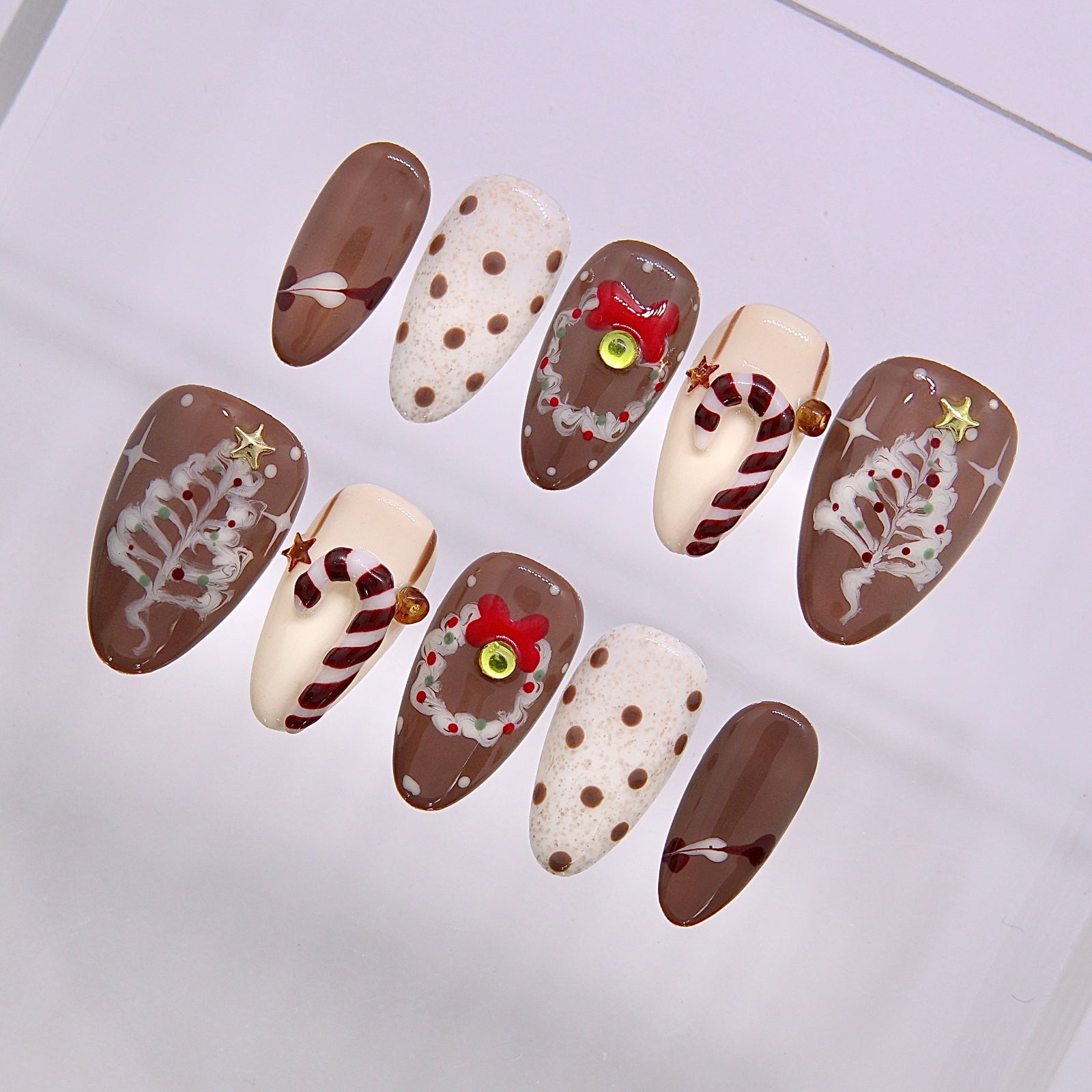 Close up of Gingerbread Latte nail art showing gingerbread motifs soft latte brown base and white frosting like lines.