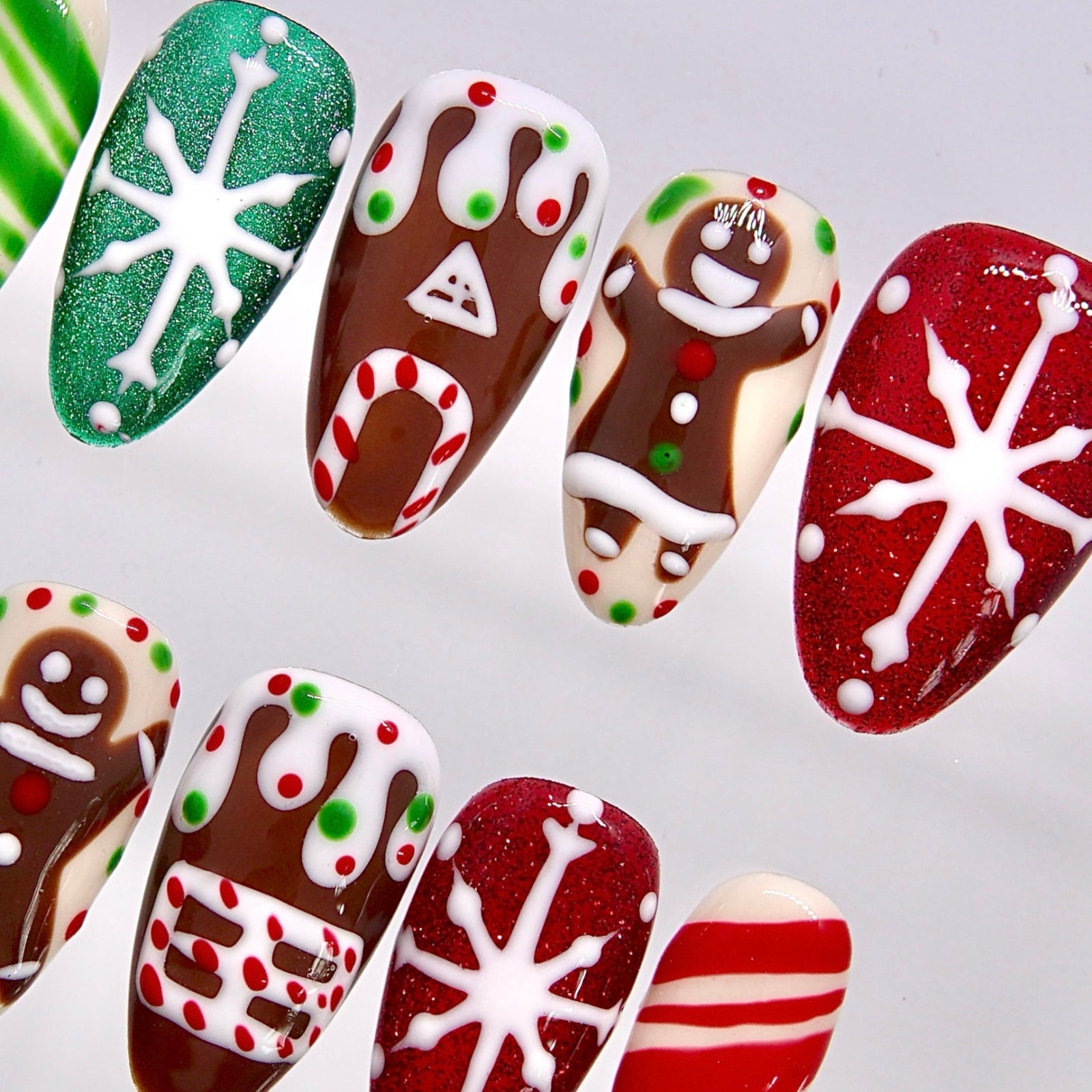 Festive Christmas press-on nails with red glitter, green shimmer, and snowflake details