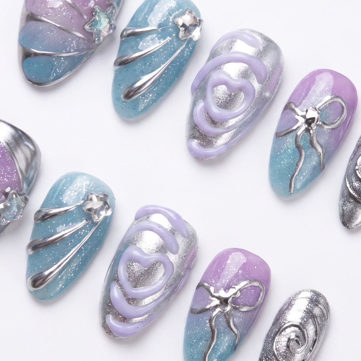 Flat lay of a pastel chrome nail set featuring sculptural silver lines and gradient tones.