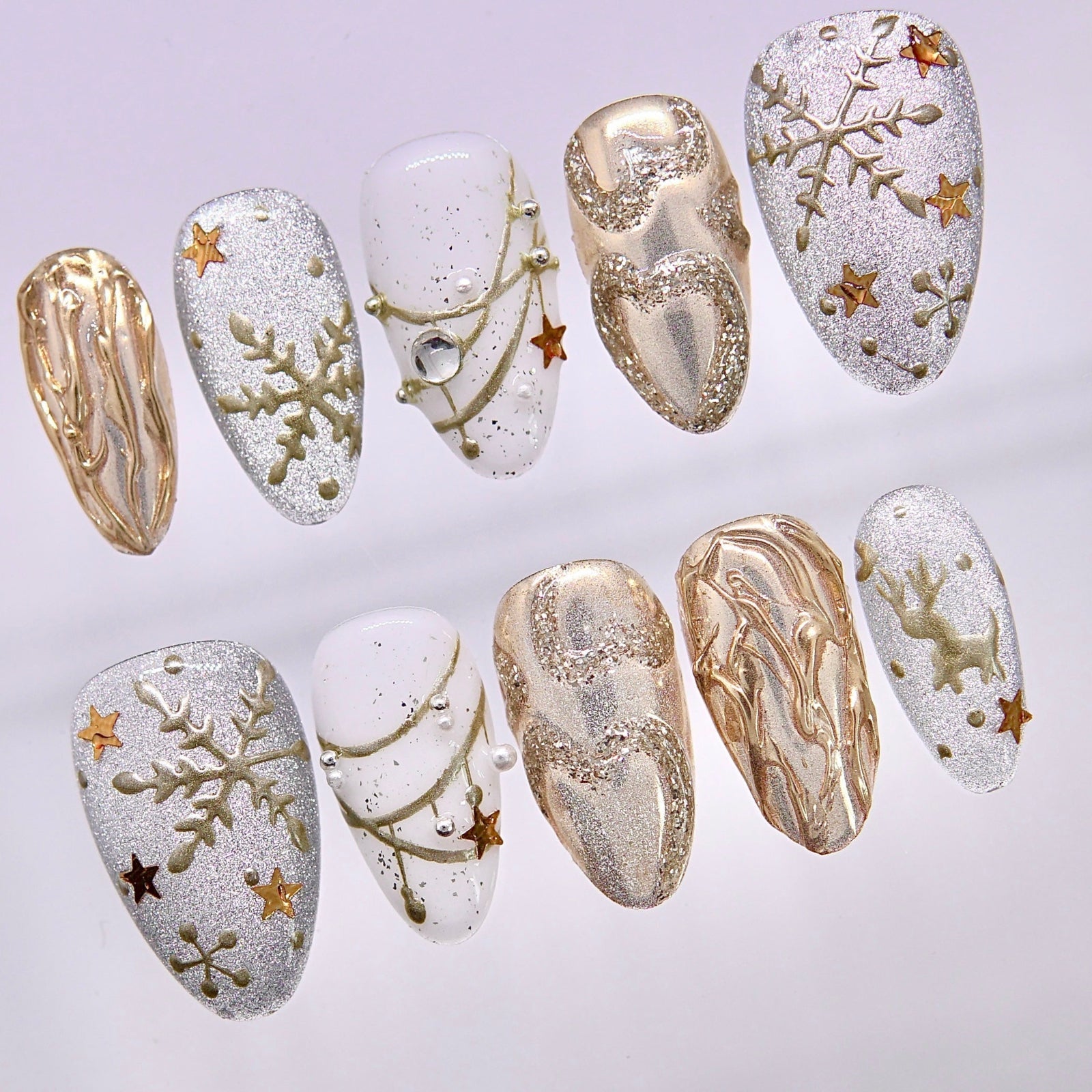 Close-up of silver and gold Christmas press-on nails with snowflakes, stars, and pearl details
