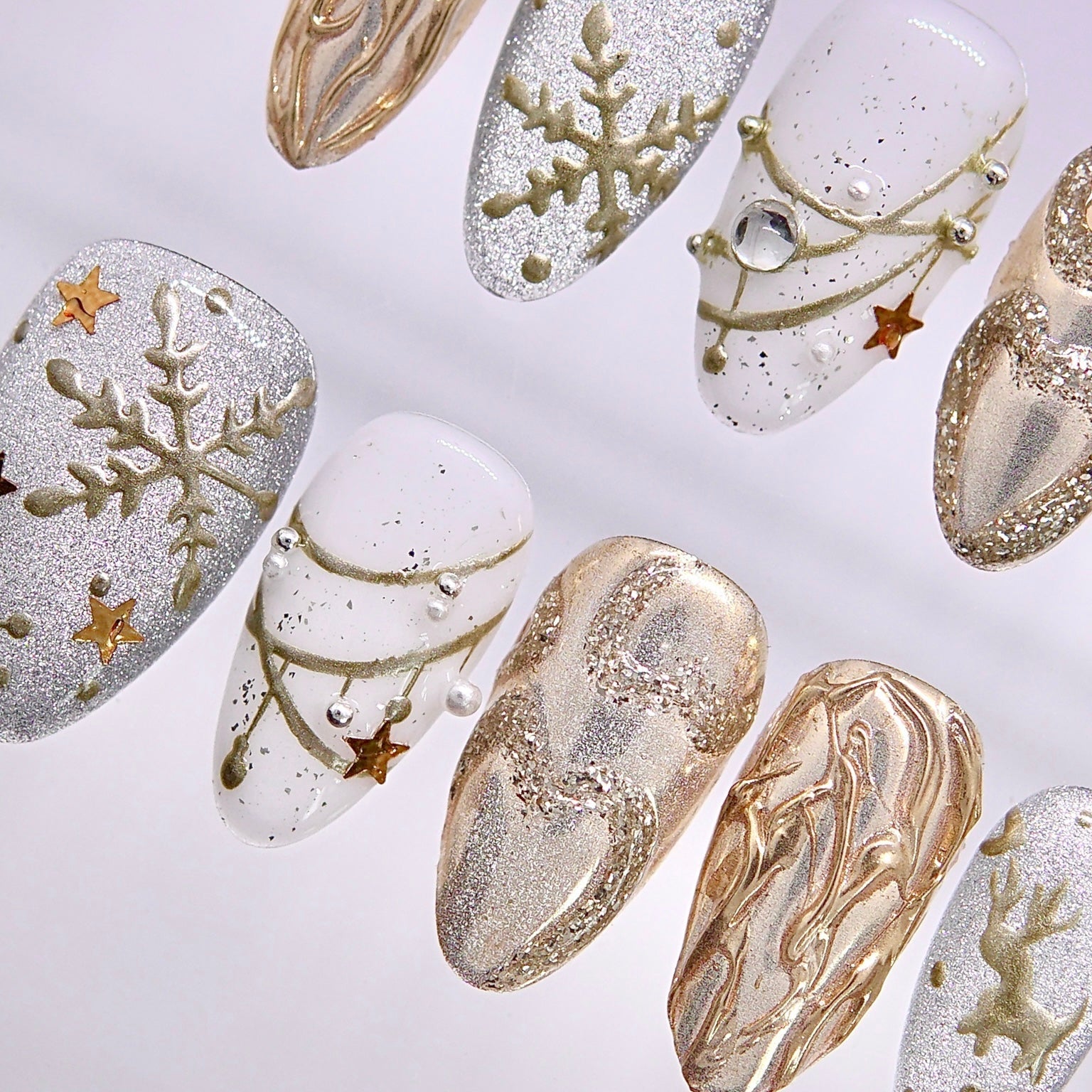 Handmade holiday press-on nails featuring sculpted metallic textures and winter-inspired designs