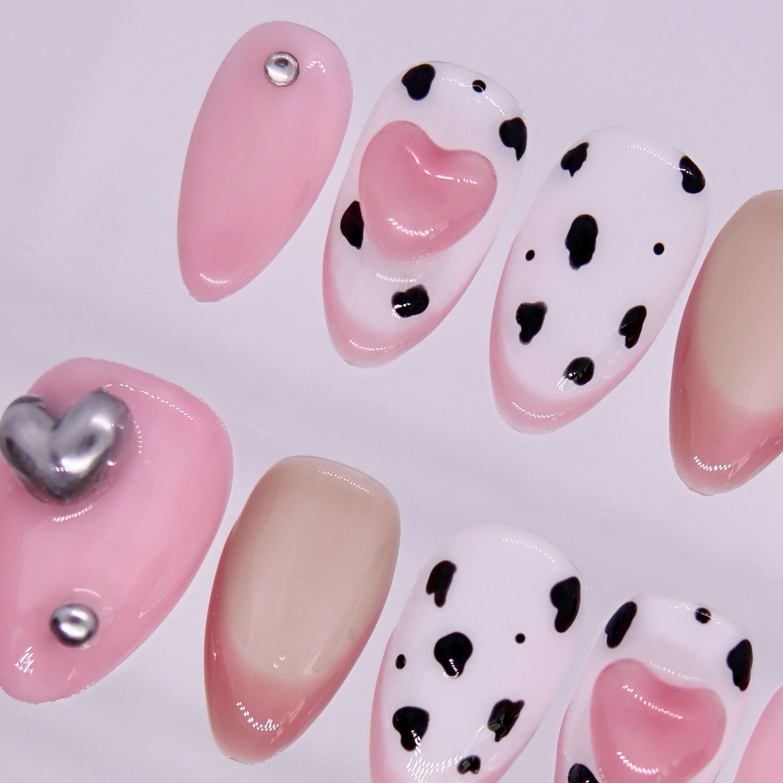 Detail view of Ox zodiac Valentine nails with creamy nude base, subtle cow-print accents, and silver embellishments.