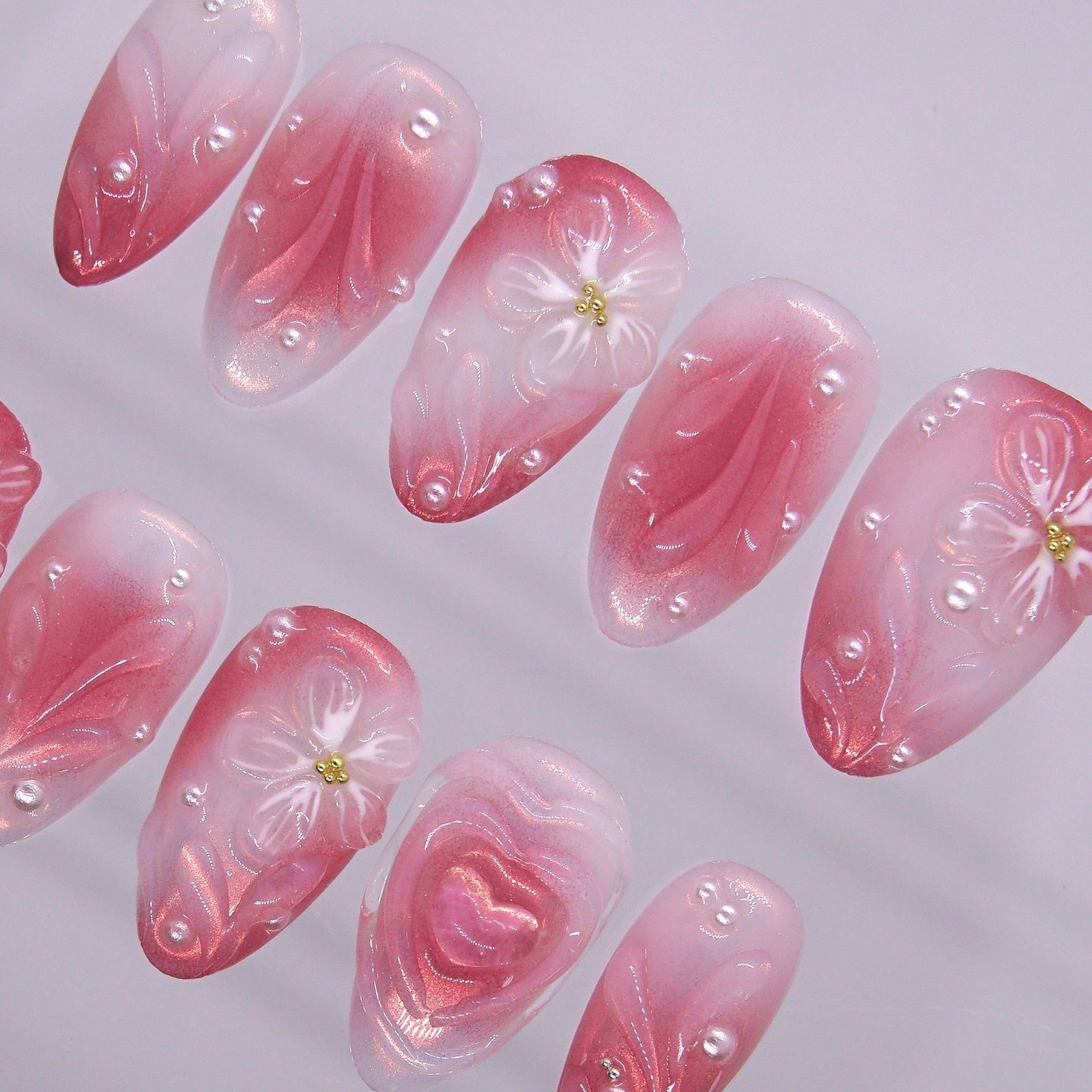 Detailed view of 3D heart centerpiece with shimmer finish on soft girl press-on nails.
