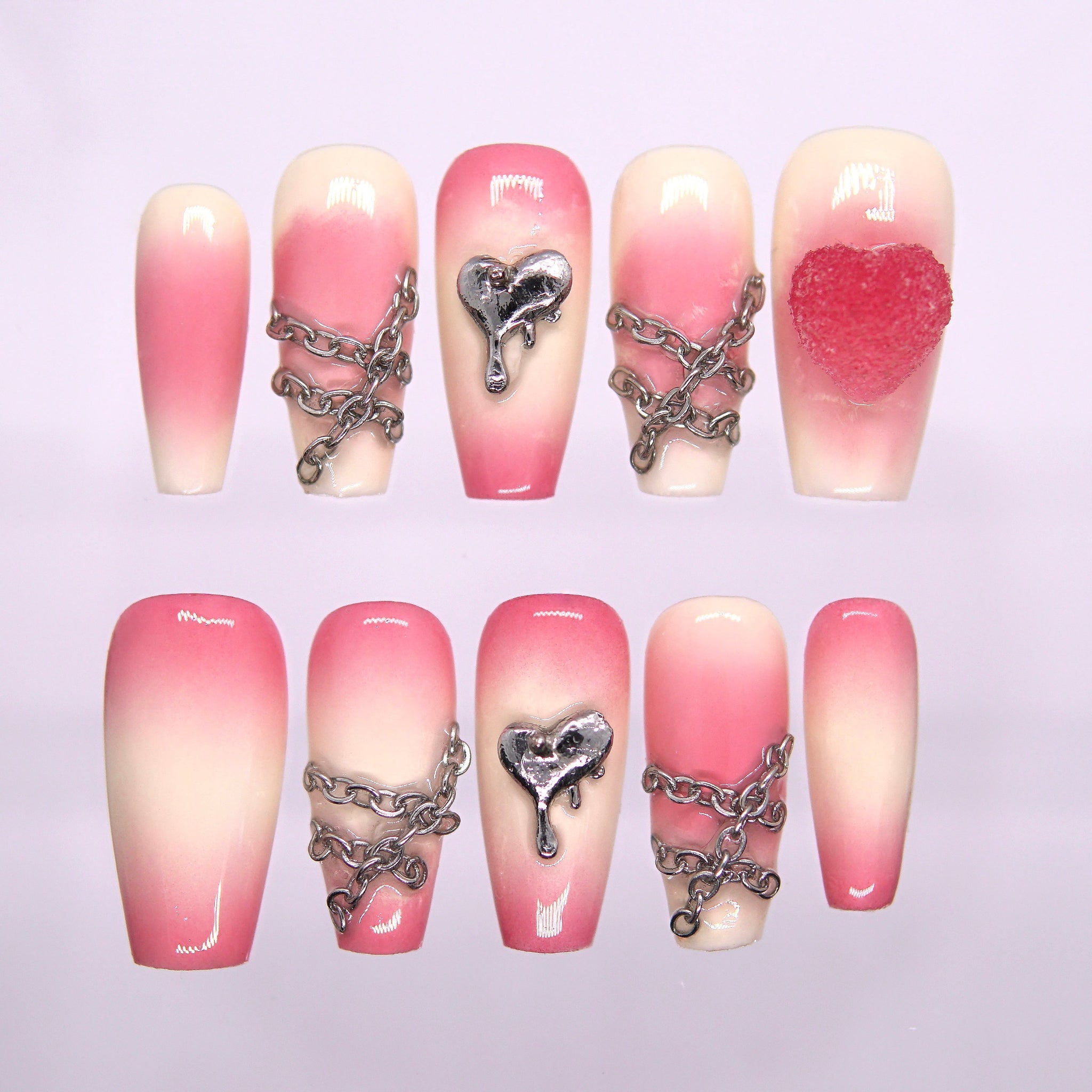 Pink-to-cream gradient press-on nails with silver chains and dripping heart charm – sweet yet edgy Fire Series design by Nailsium.