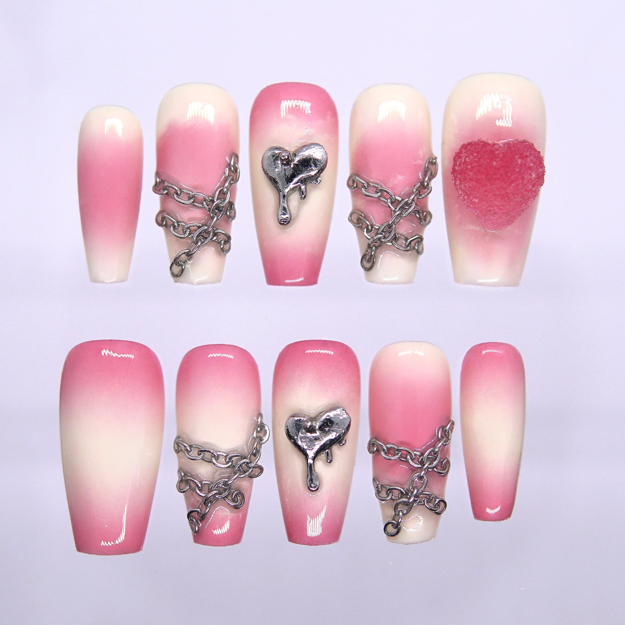 Pink-to-cream gradient press-on nails with silver chains and dripping heart charm – sweet yet edgy Fire Series design by Nailsium.