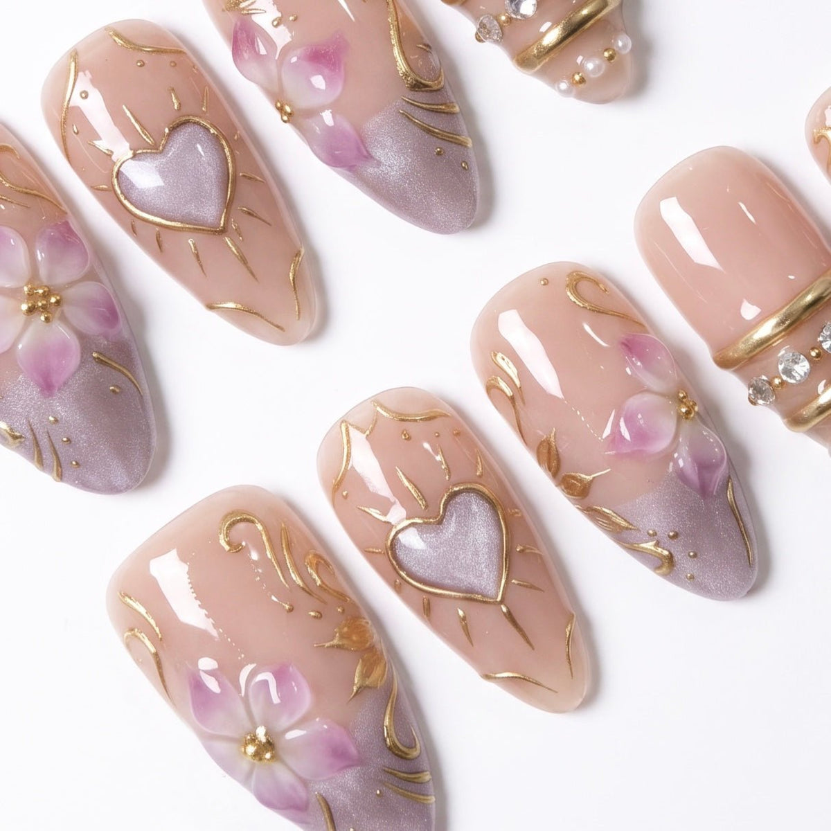 Detailed view of Heartspell Garden nail art with sculpted lilac petals, glowing heart-inspired accents, gold scrollwork, and crystal embellishments