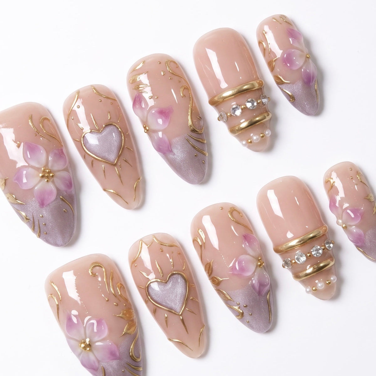 Close-up of Heartspell Garden press-on nails featuring purple floral details, a dimensional heart design, delicate gold vines, and crystal accents