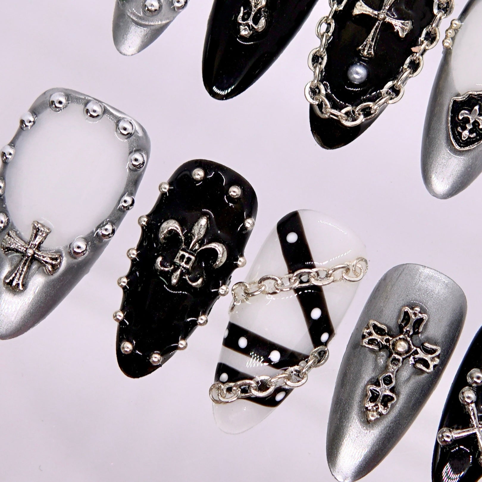 Angle view of chain-draped nail with studded lattice and pearl accents.