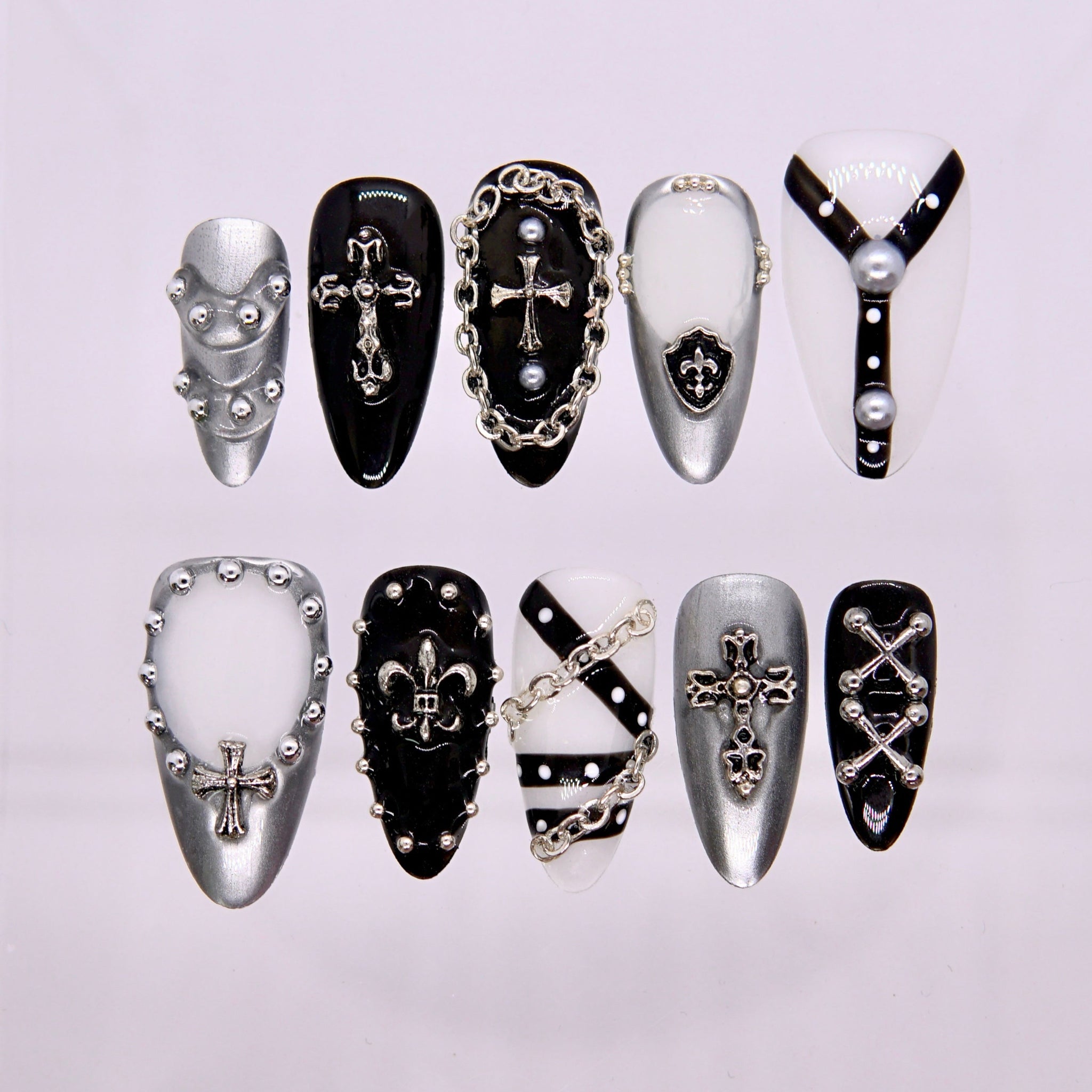 Holy Riot press-on nails in black, white, and chrome with cross charms, chains, and studs.