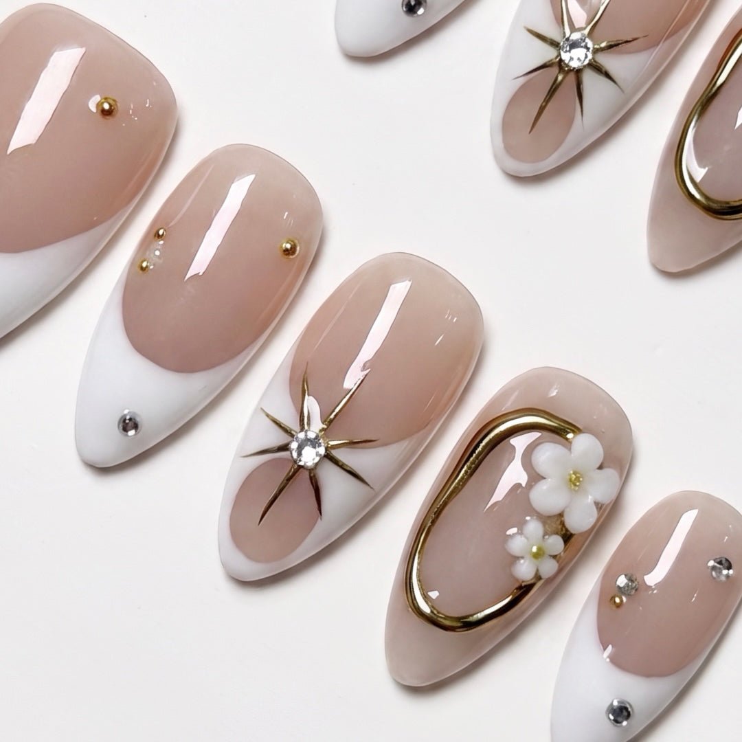 Close-up of soft nude nails with white tips and small crystal details