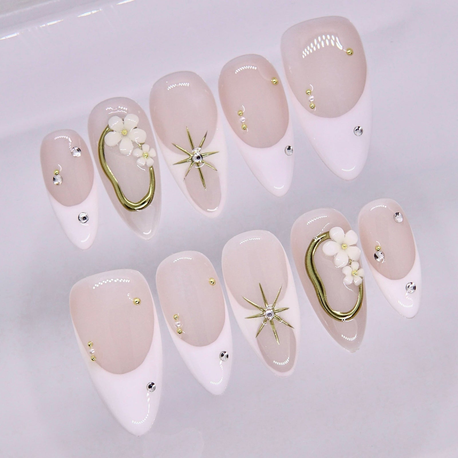 Close-up of soft nude nails with white tips and small crystal details