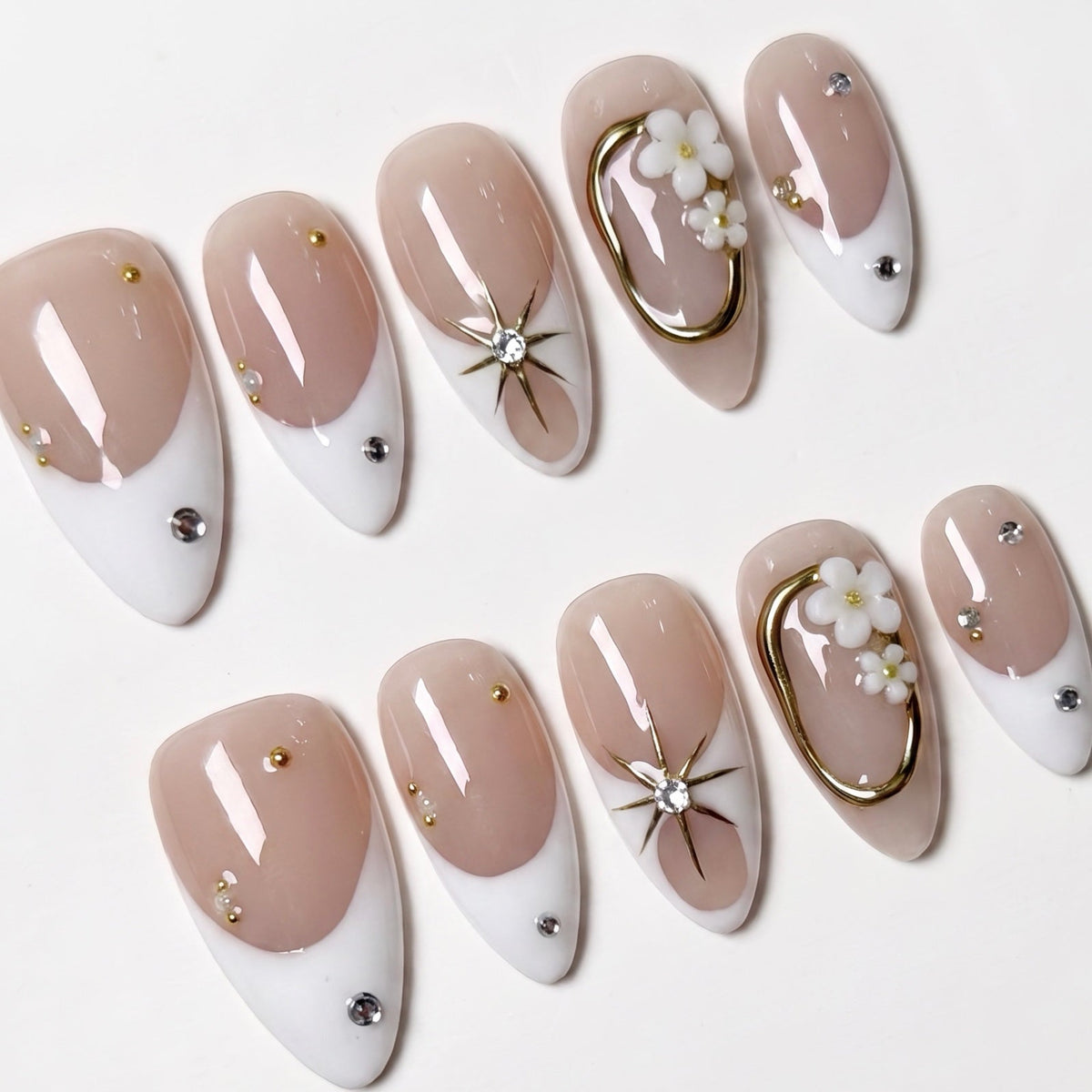 Close-up of soft nude nails with white tips and small crystal details