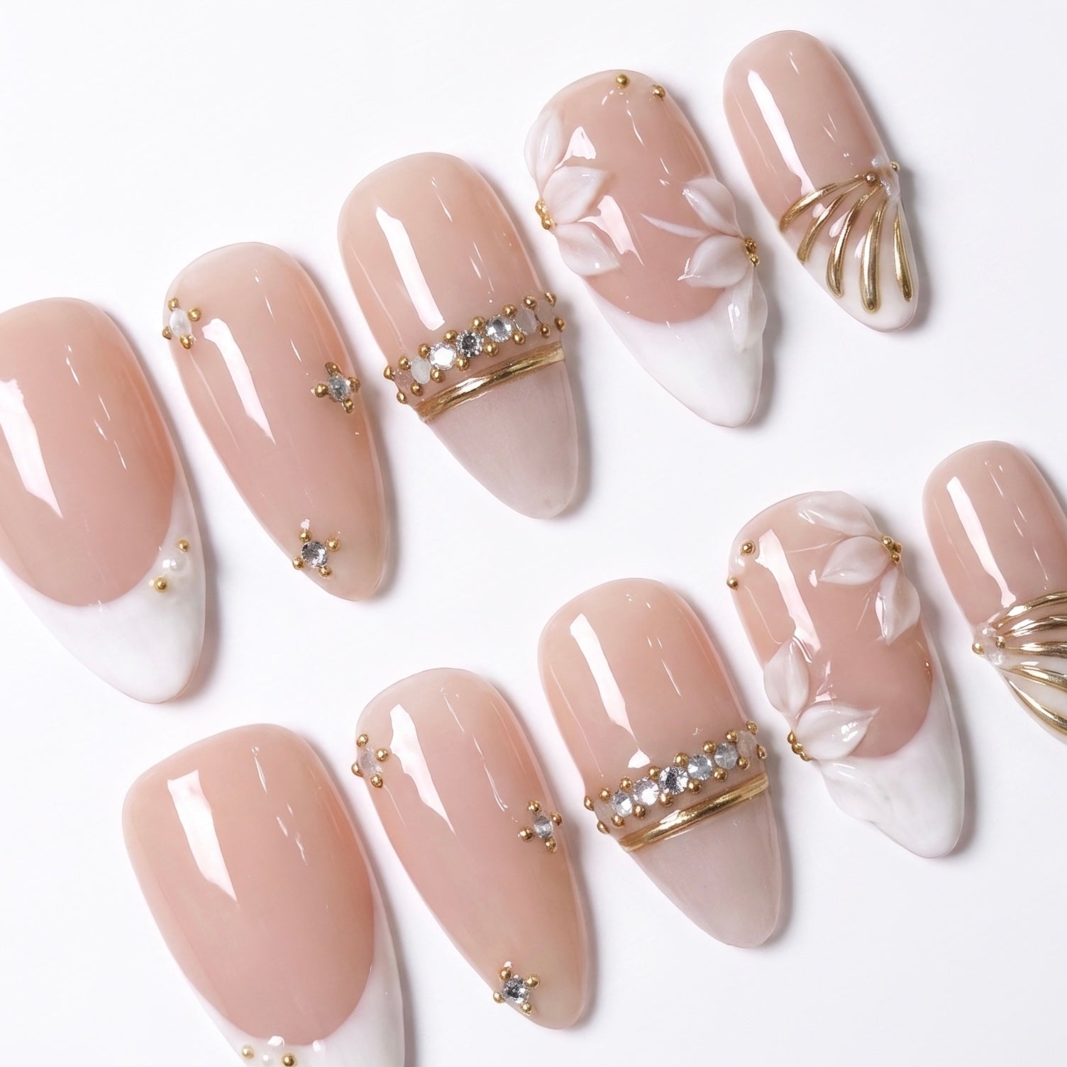 Close-up of Ivory Petal Waltz press-on nails featuring dimensional ivory flower petals, crystal ring-band details, tiny pearls, and gold accents