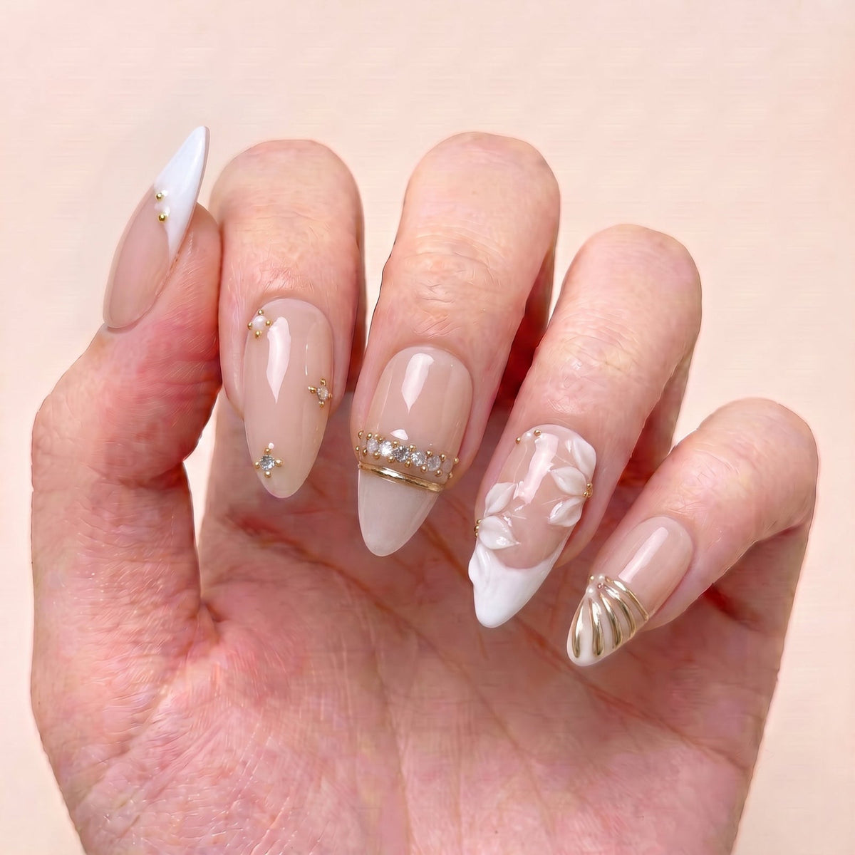Ivory Petal Waltz handmade press-on nails worn on hand with nude blush tones, ivory floral details, crystal accents, and delicate gold embellishments