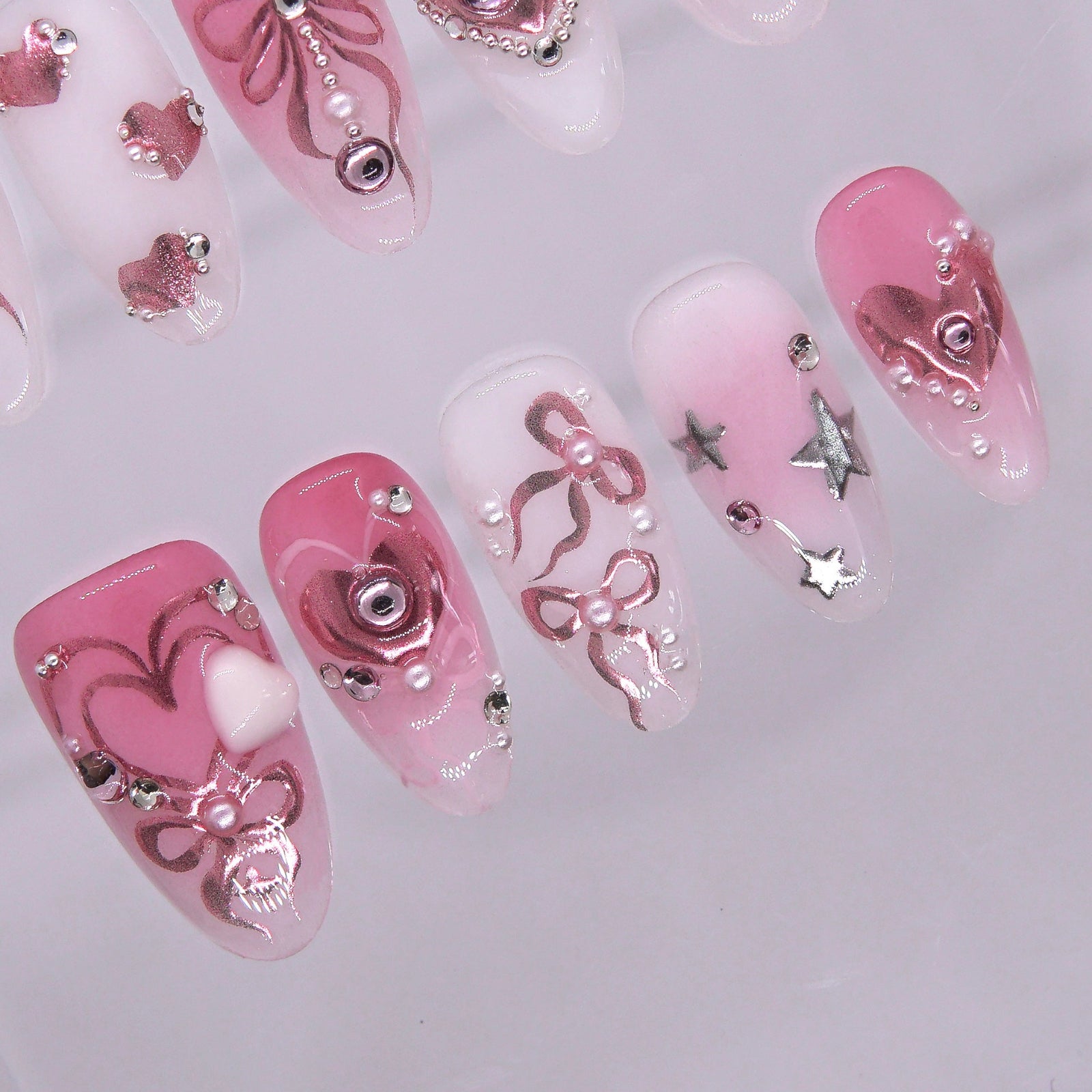 Metallic pink heart press on nails with star details and glossy finish.