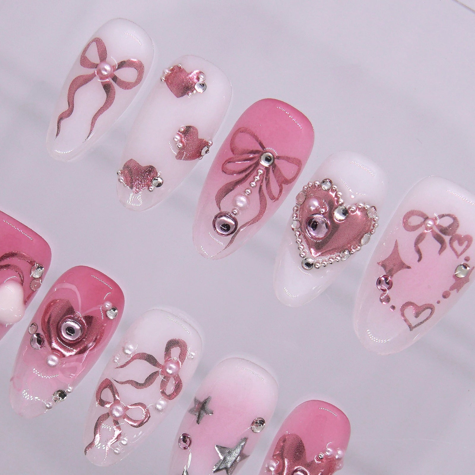 Metallic pink heart press on nails with star details and glossy finish.