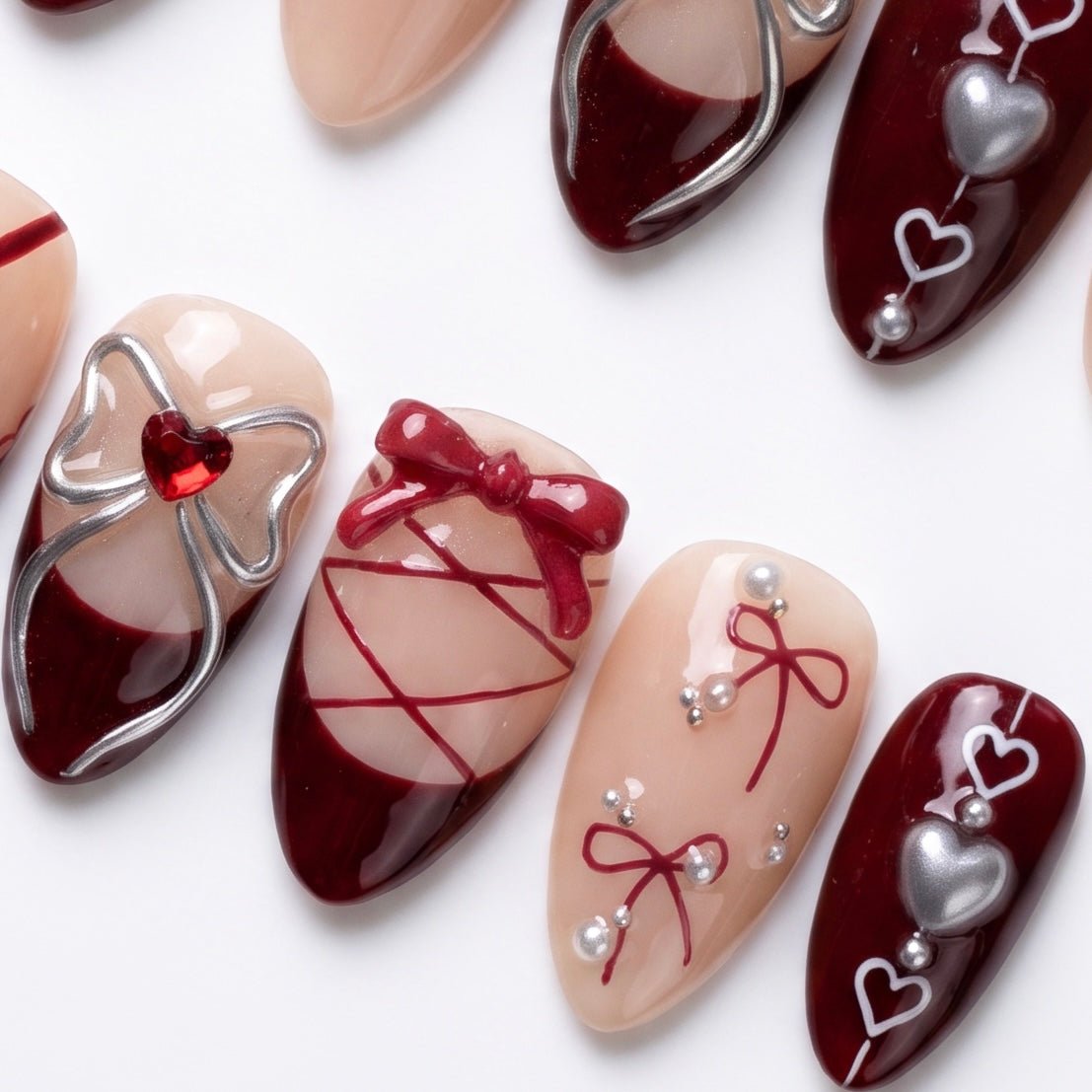 Close-up of lace-up nail design with silver bows and heart charms.
