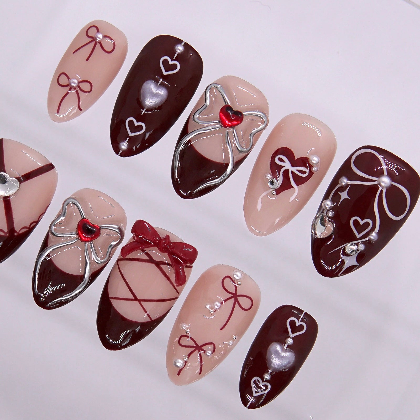 Close-up of lace-up nail design with silver bows and heart charms.