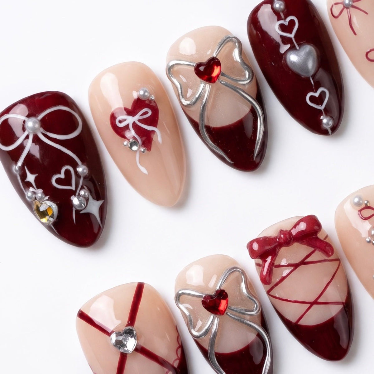 Close-up of lace-up nail design with silver bows and heart charms.