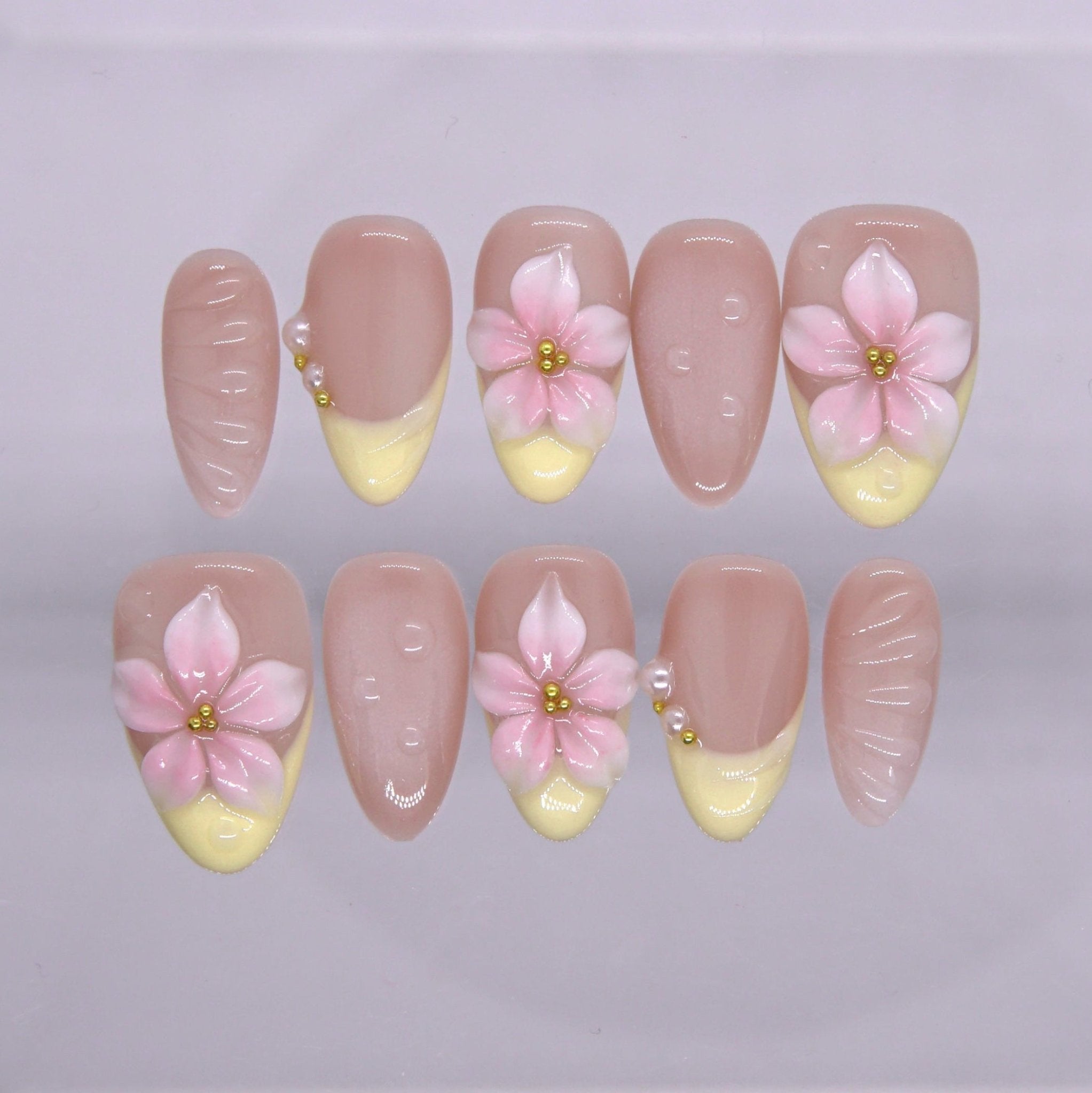 Yellow French tip press on nails with 3D pink flower and gold bead detail.