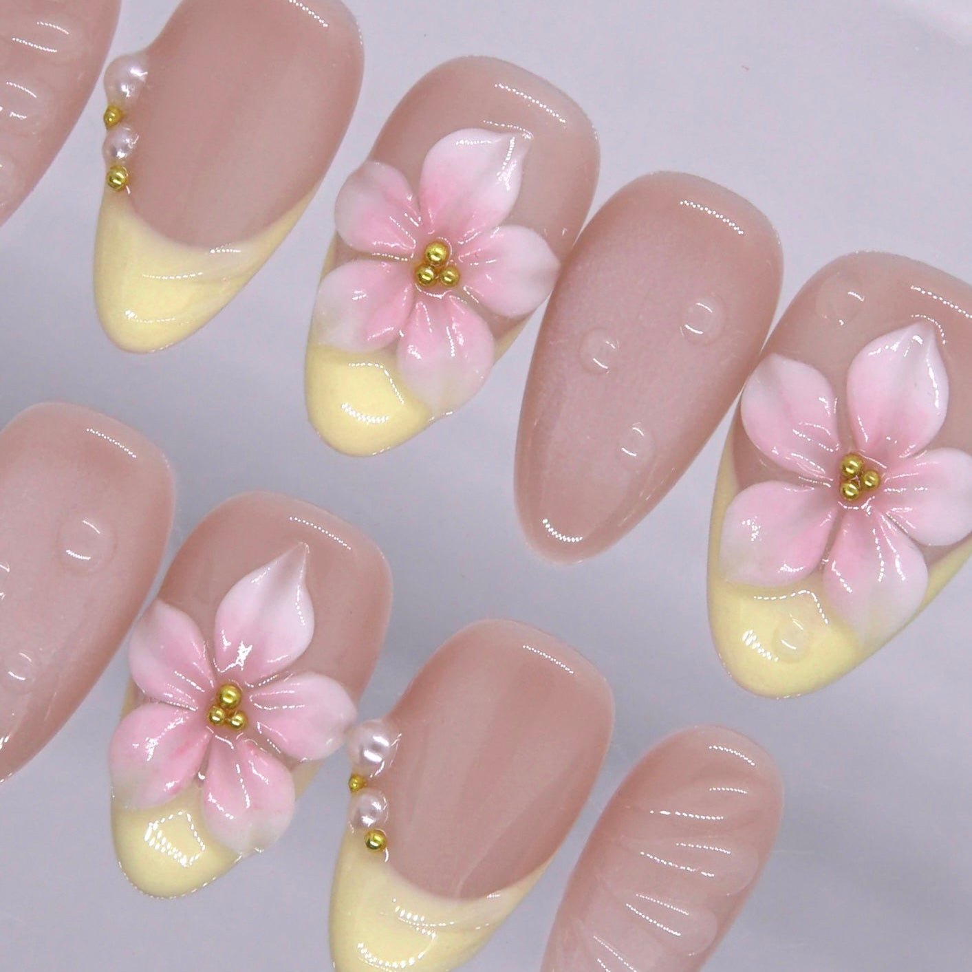 Glossy nude base almond shaped press on nails with pearl accent.
