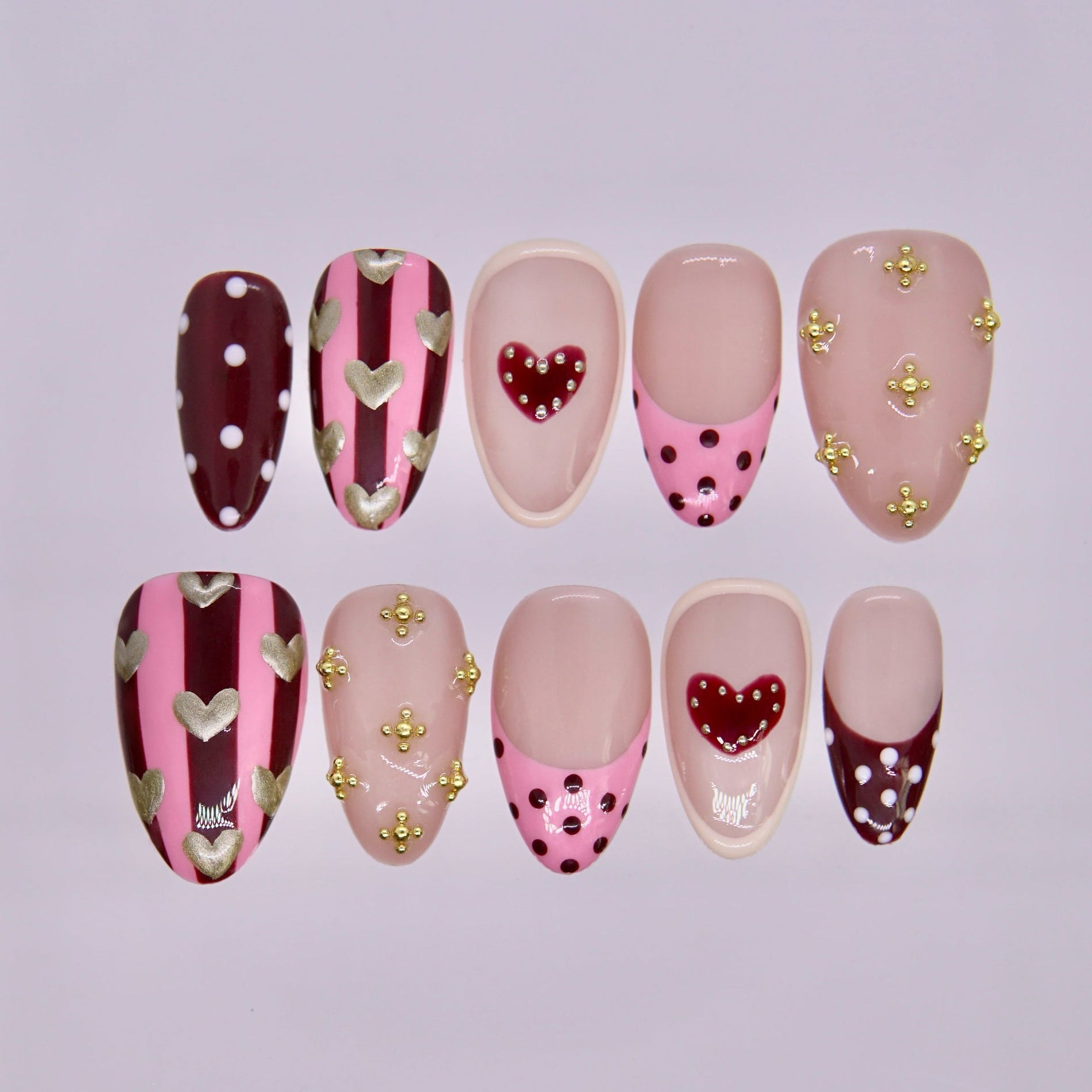 Horse zodiac press-on nails in blush nude with pink and burgundy heart and stripe designs, representing Liberty and free spirited self love.
