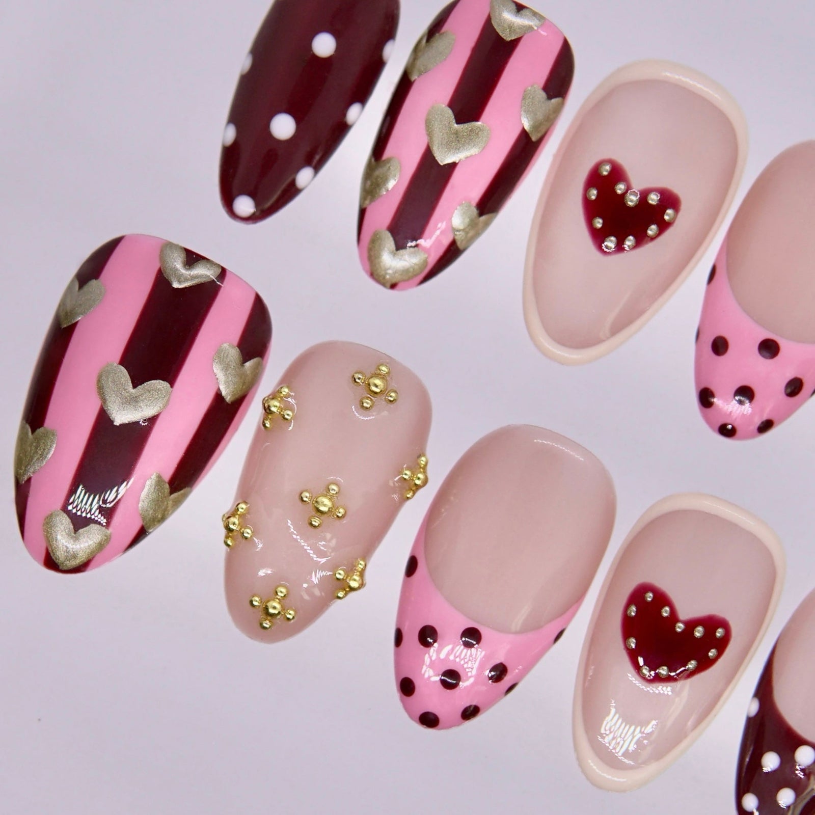 Detail view of Horse zodiac Valentine nails showing blush nude base with heart motifs, dotted tips, and expressive color contrasts.