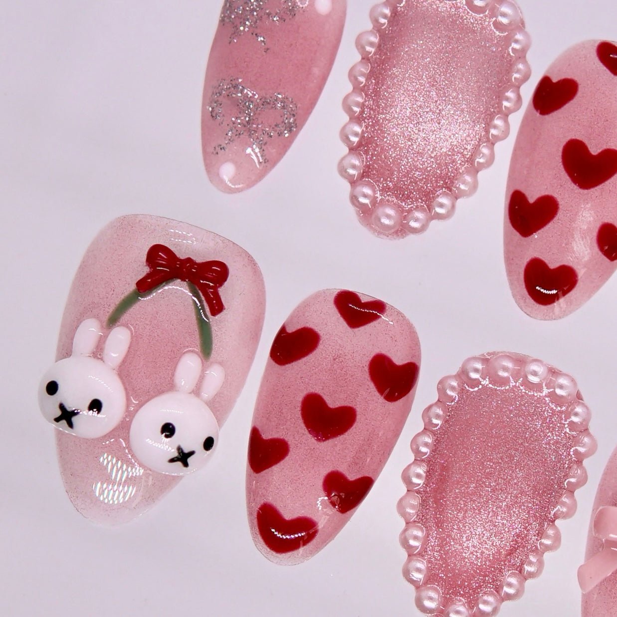 Detail view of Rabbit zodiac Valentine nails with soft pink tones, bow accents, and playful bunny charm details.