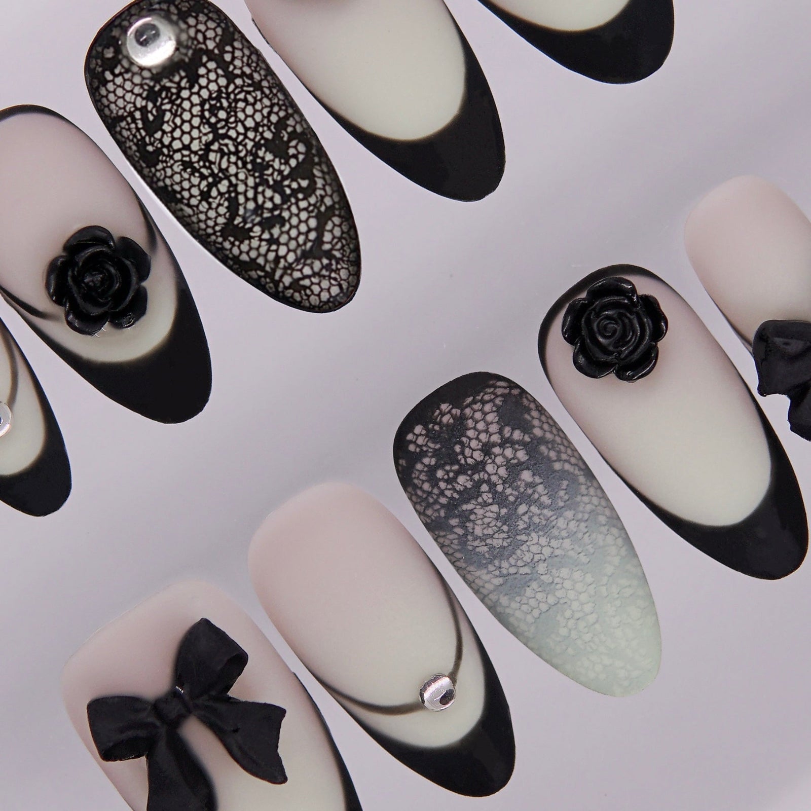 Matte gradient press on nails decorated with black roses and bows.