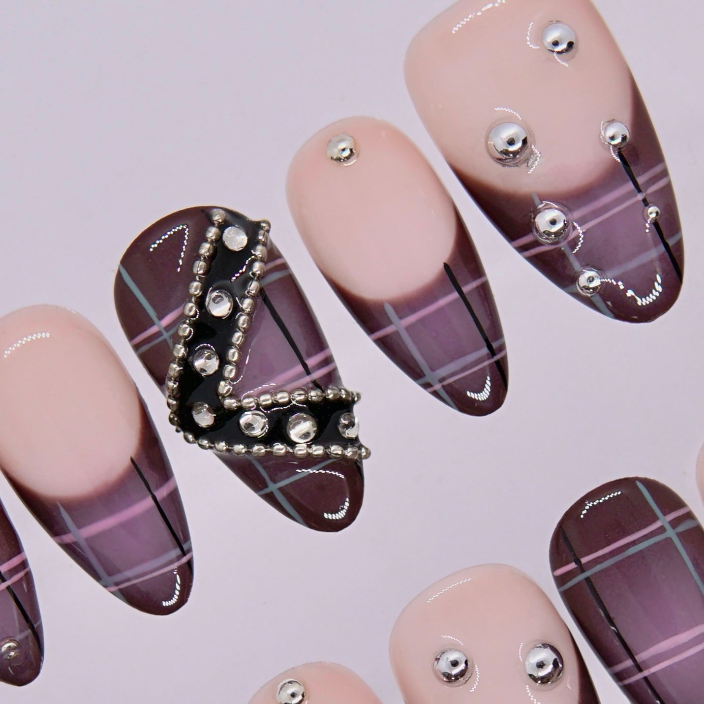 Side angle view of Mocha Rebel press-on nails highlighting glossy plaid and silver accents.