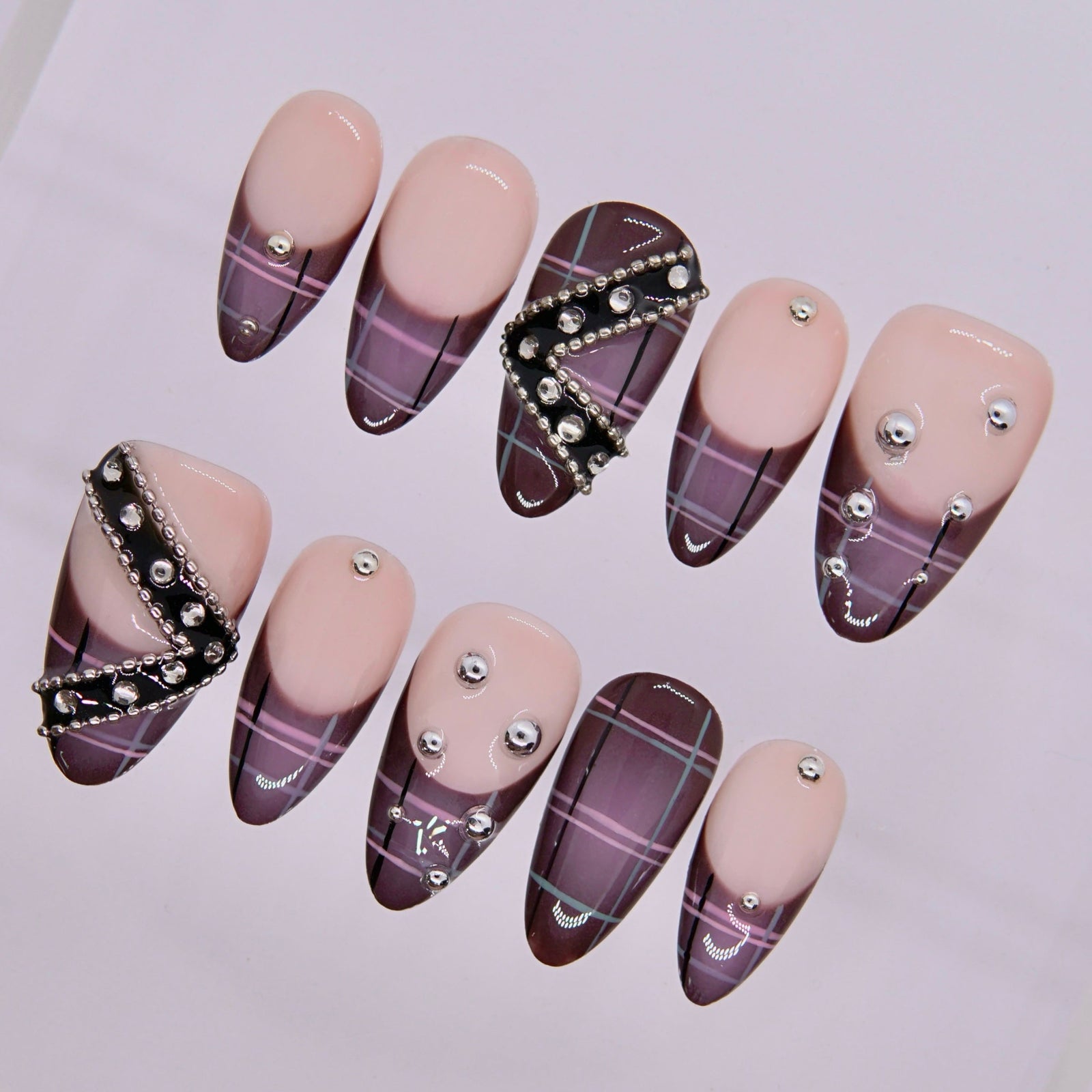 Close-up of Mocha Rebel nails showing metallic chain and bead embellishments.