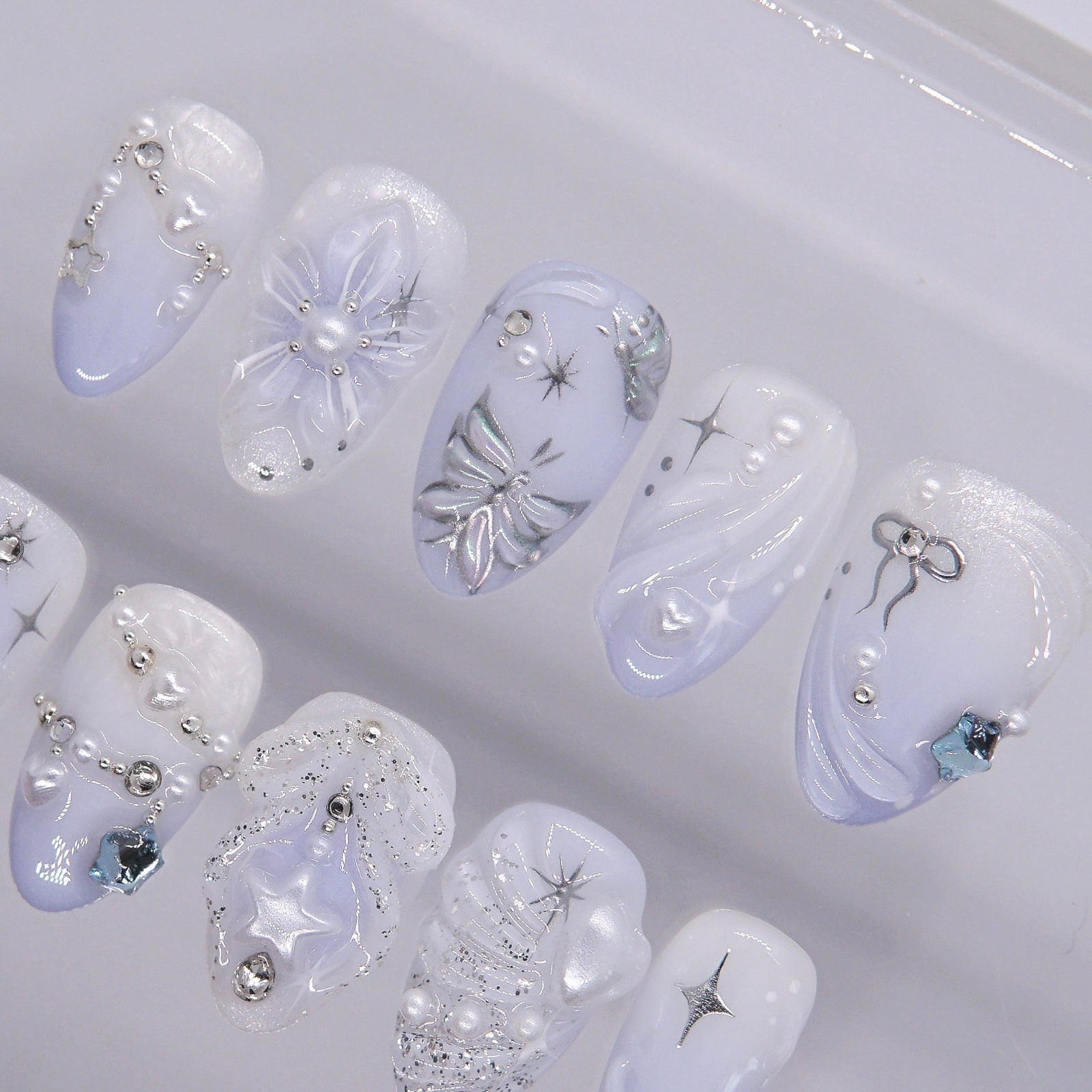 Soft pearly white and icy blue press-on nails with glowing pearls and glitter accents.
