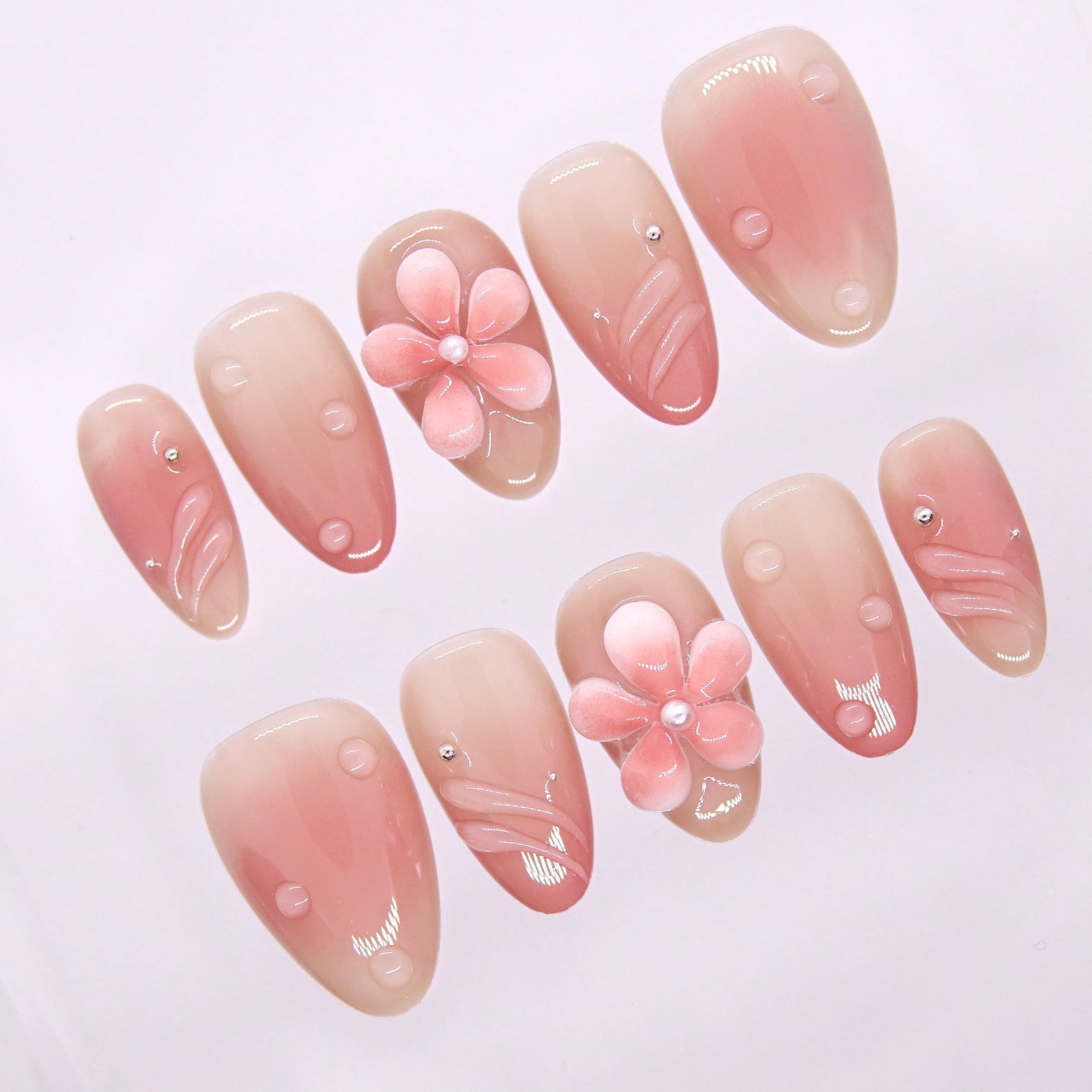 Glossy nude-pink press-on nails with soft water-like dew-drop details for a fresh, natural vibe.