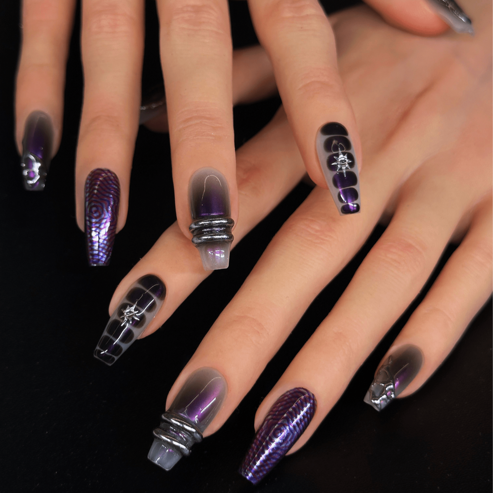 Both hands wearing Night Bloom press-on nails in deep purple gradient with silver chrome textures and holographic details — modern night club vibe.