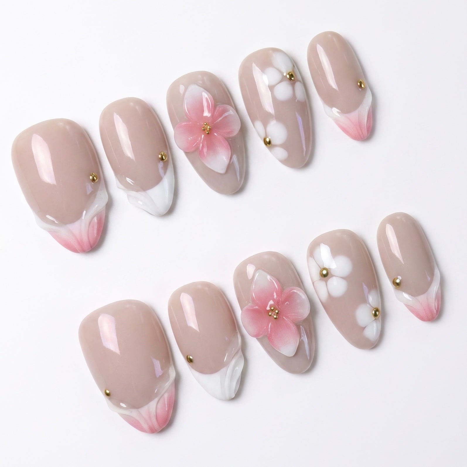Close-up of handmade peach floral press-on nails with sculpted 3D flowers, soft nude base, and gold embellishments