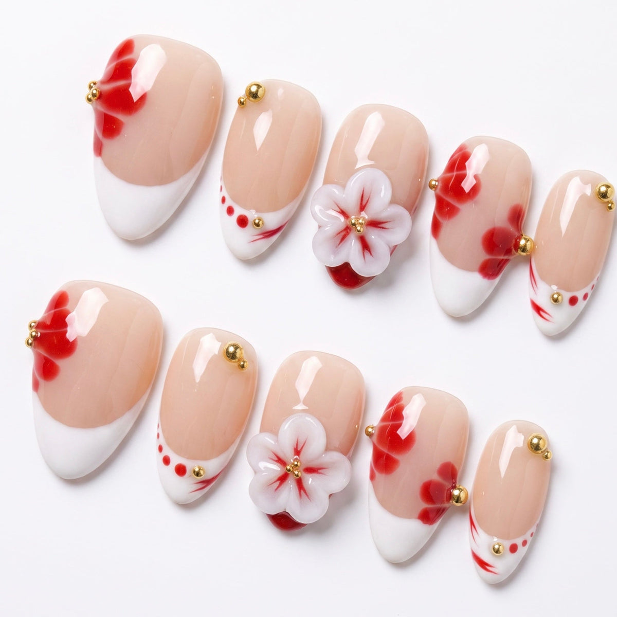 Close-up of red petal-inspired nail art with gold bead details