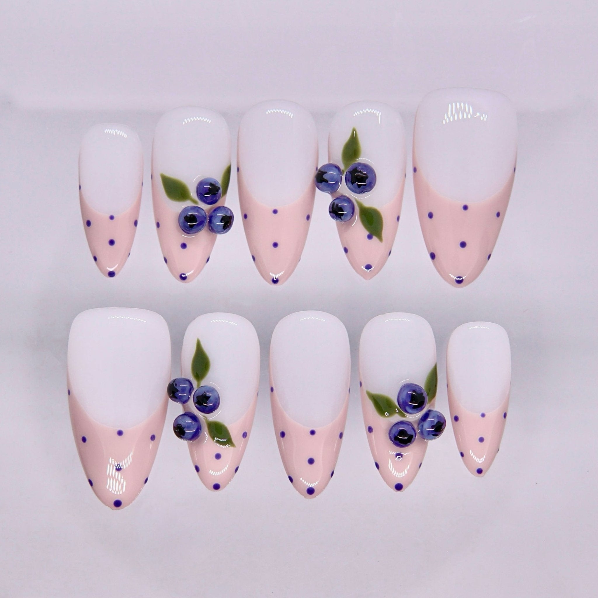 Soft pink press on nails with blue dot accents and blueberry-inspired design