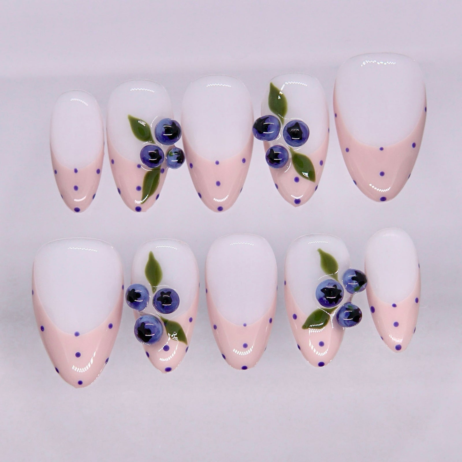 Soft pink press on nails with blue dot accents and blueberry-inspired design