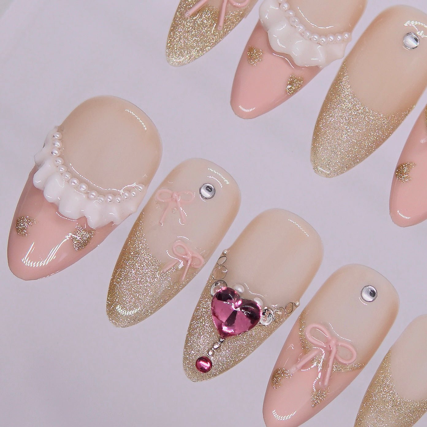 Close-up of handcrafted bow and crystal heart detail on Ribbon Agenda press-on nail design