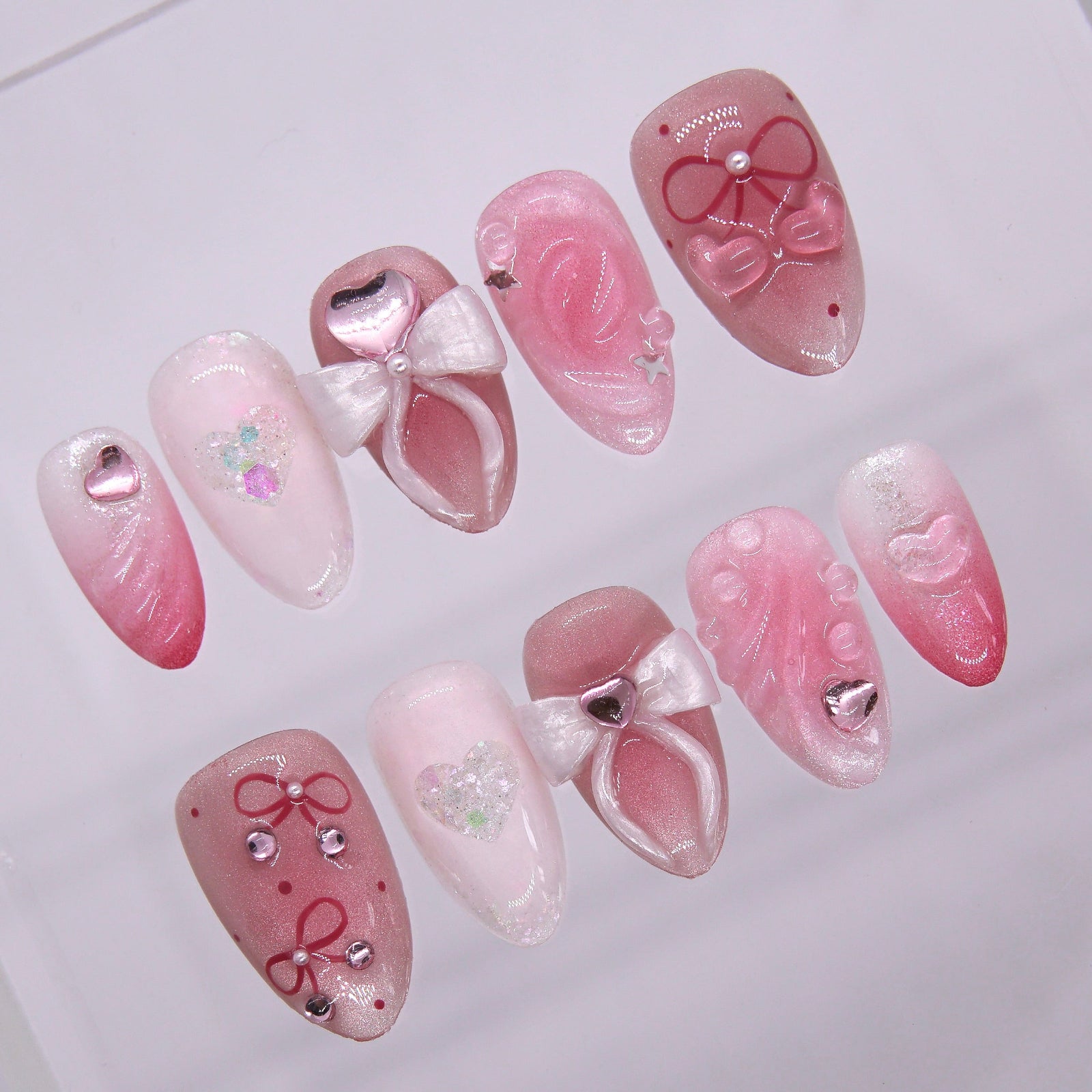 Close-up of 3D white bow on a blush pink nail, with heart gem accent and pearly finish.