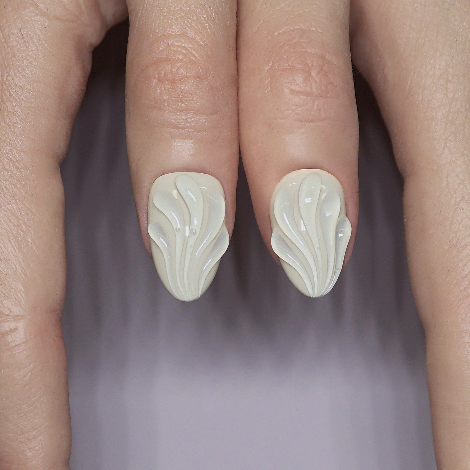 Model wearing Rosewater Shell press-on nails in a cozy neutral-toned outfit, showcasing soft sculpted designs in natural light.