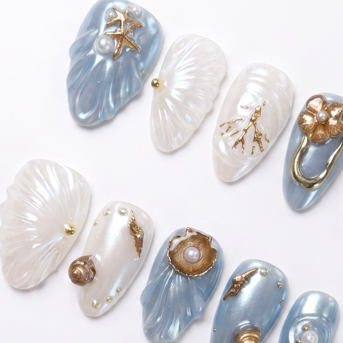 Blue and white sculpted nails with coral branches, shell ridges, and metallic gold details.