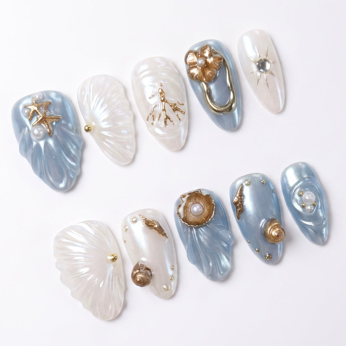 Close-up of 3D seashell press on nails featuring bronze ocean charms and pearl accents.