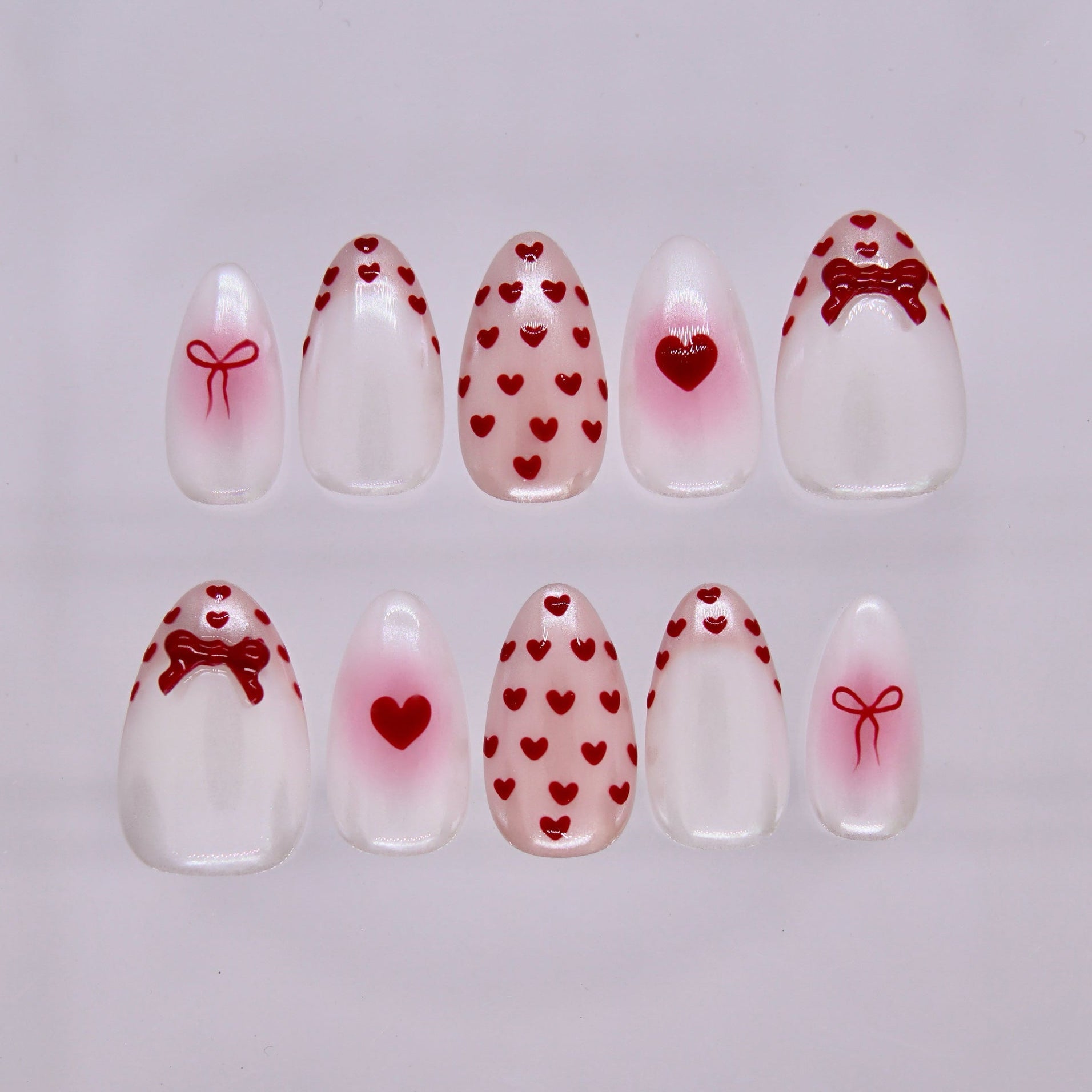 Goat zodiac press-on nails in milky white with red heart and bow details, representing Serene self love and emotional calm.